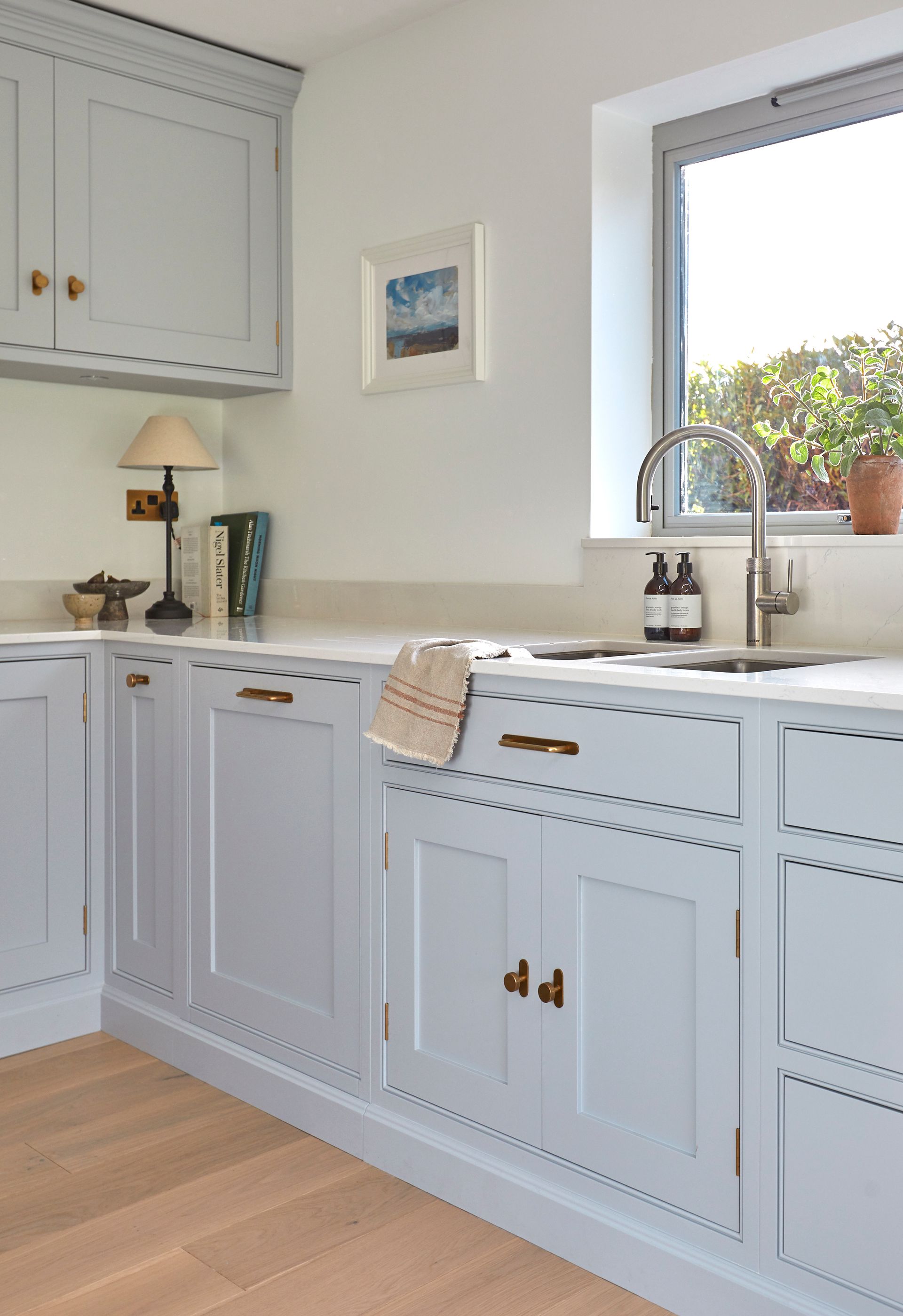 a shaker style kitchen with a sink and a picture on the wall above it