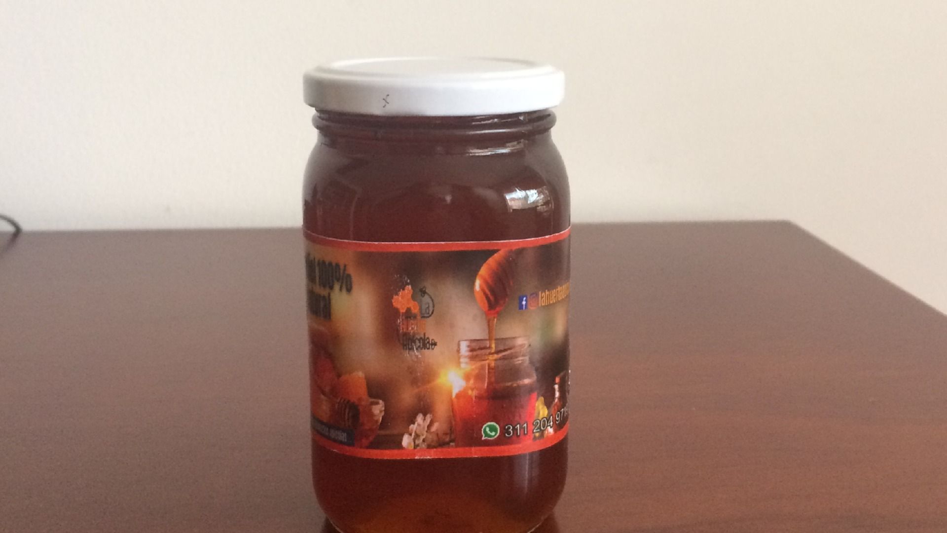 Tarro de miel con etiqueta sobre una mesa.
