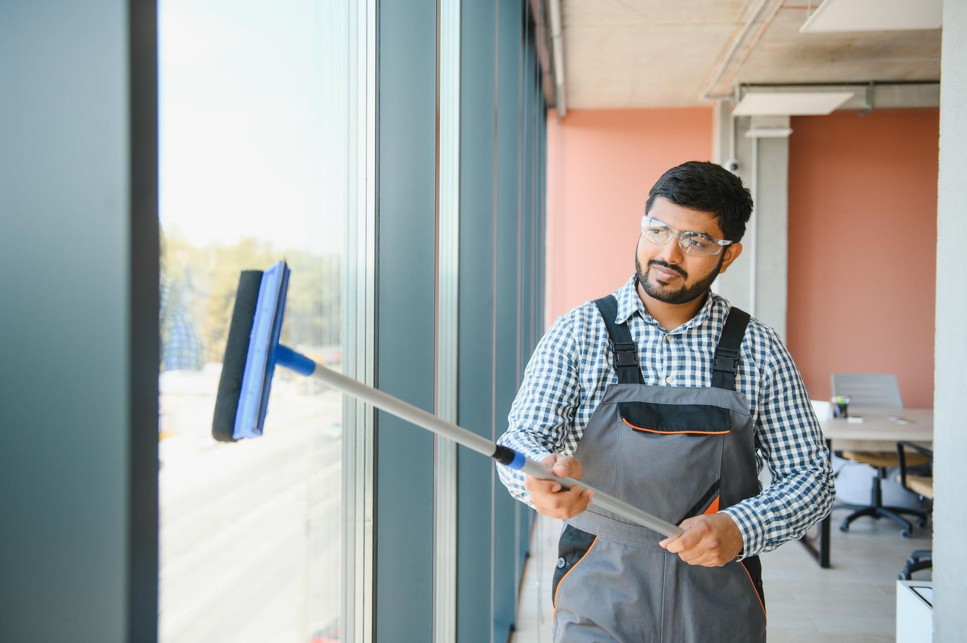 A man is cleaning a window with a mop.