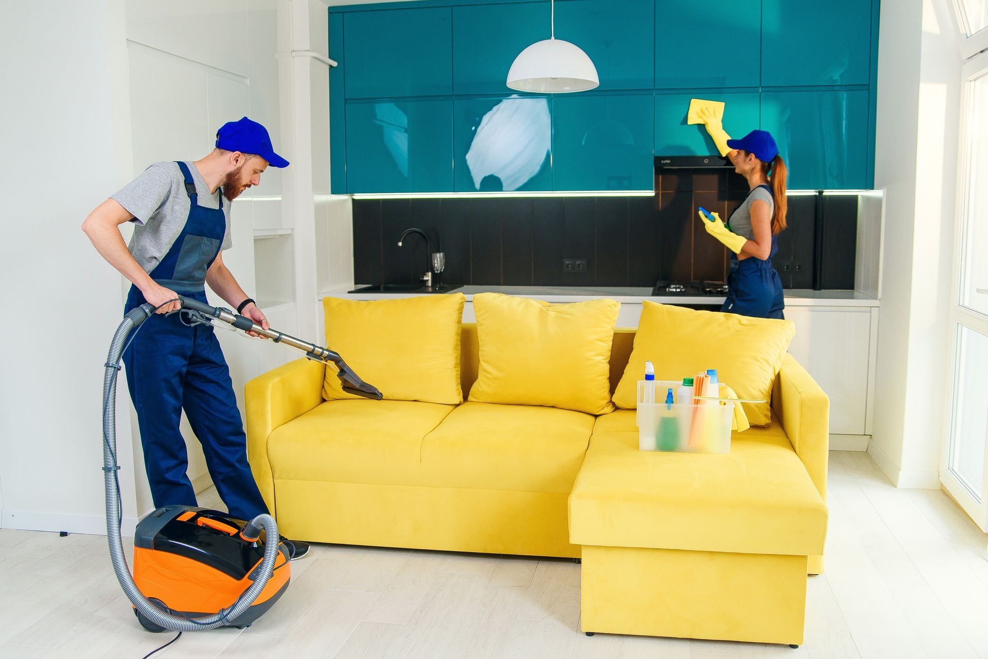 A man and a woman are cleaning a living room with a vacuum cleaner.
