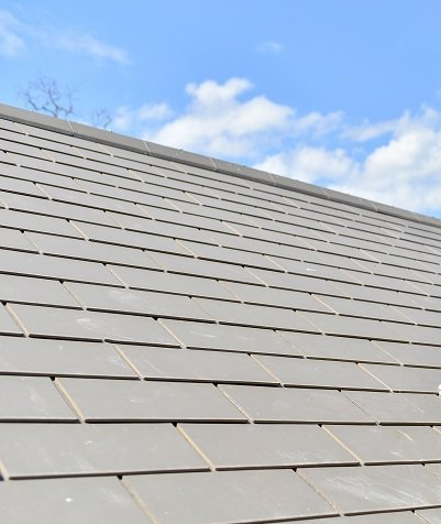 A large house is sitting on top of a lush green lawn on a rainy day.