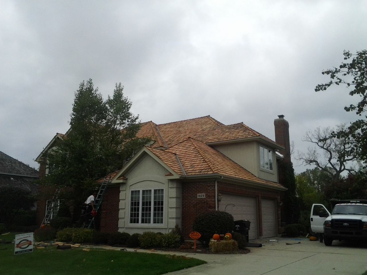A white truck is parked in front of a house with a tiled roof