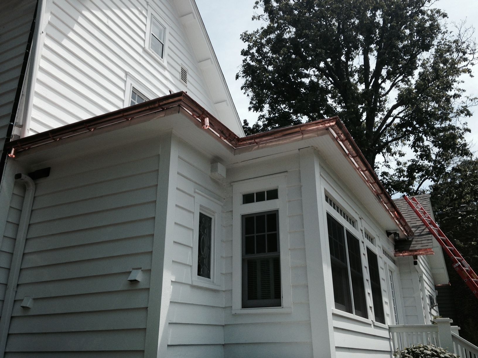 A white house with a copper gutter on the side