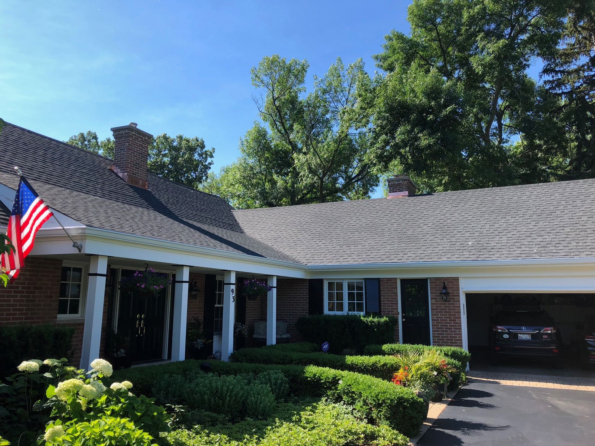 A house with a car parked in front of it and an american flag on the porch.