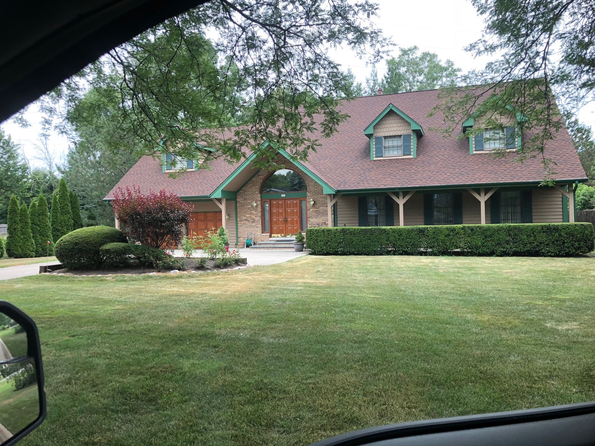 A large house with a red roof and green trim is sitting on a lush green lawn.