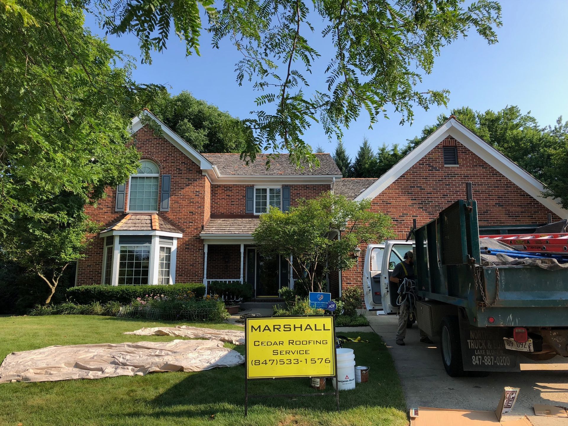 A dump truck is parked in front of a brick house.