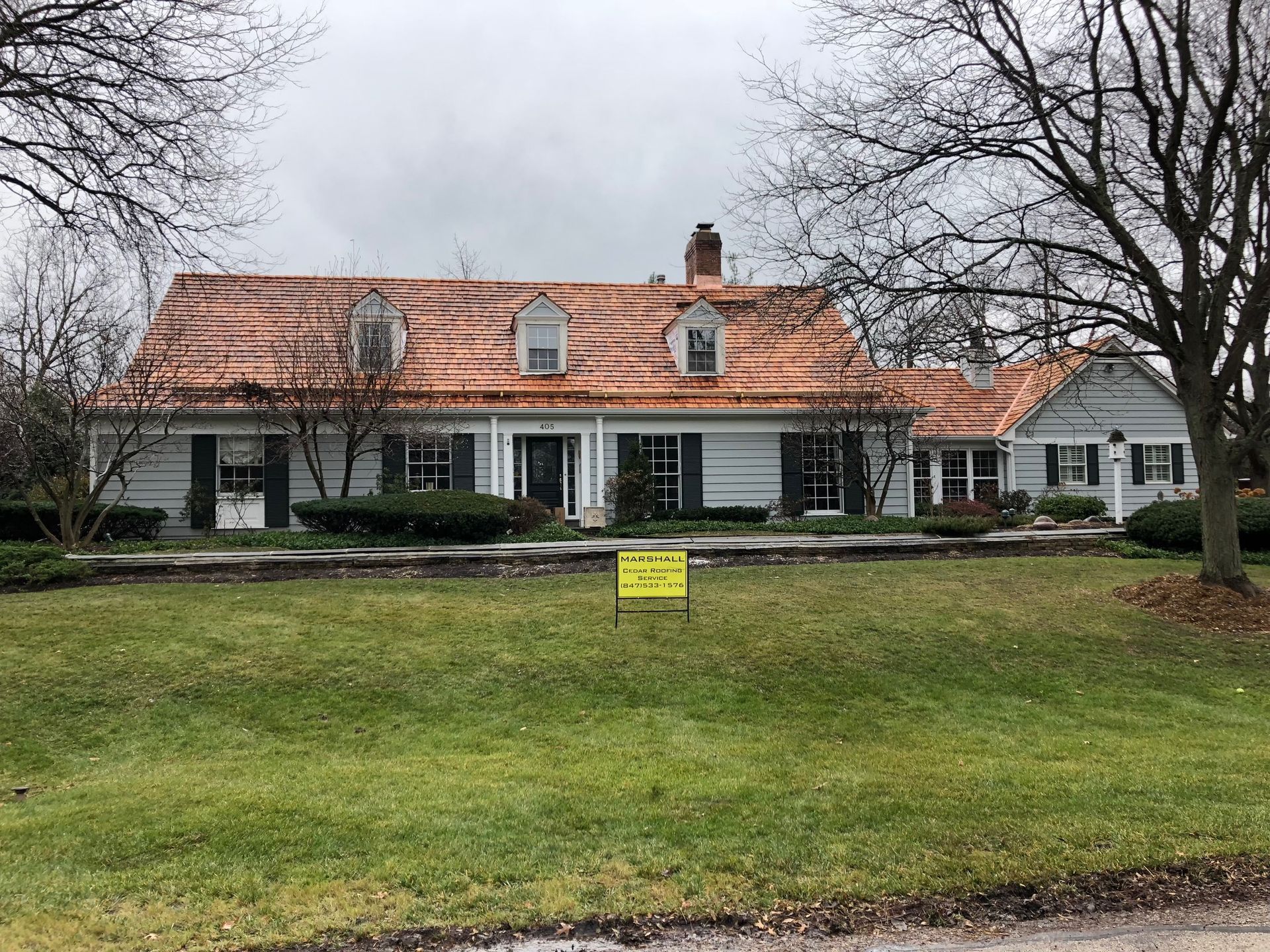 A large white house with a copper roof and a sign in front of it.