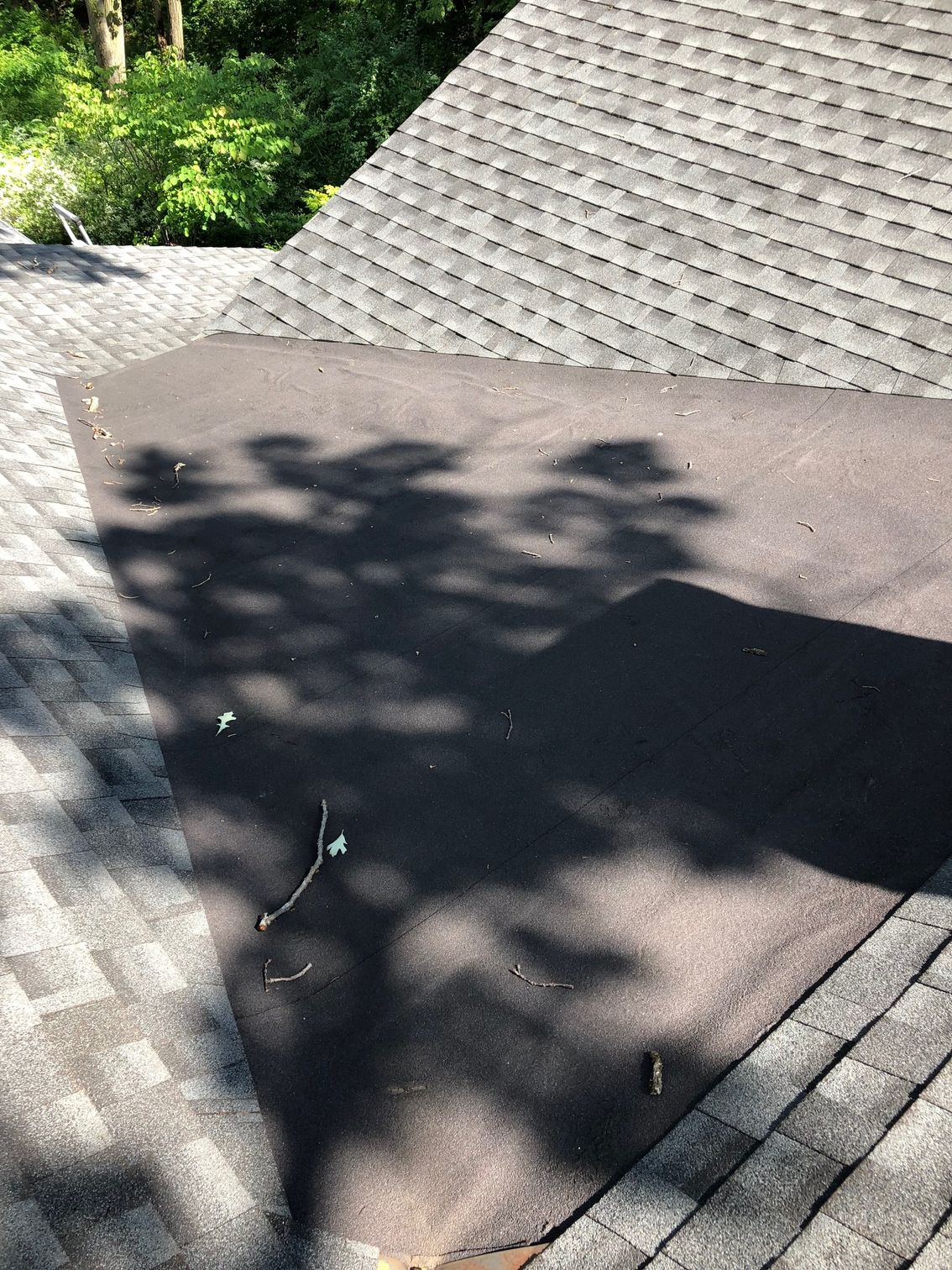 A close up of a roof with a tree shadow on it.