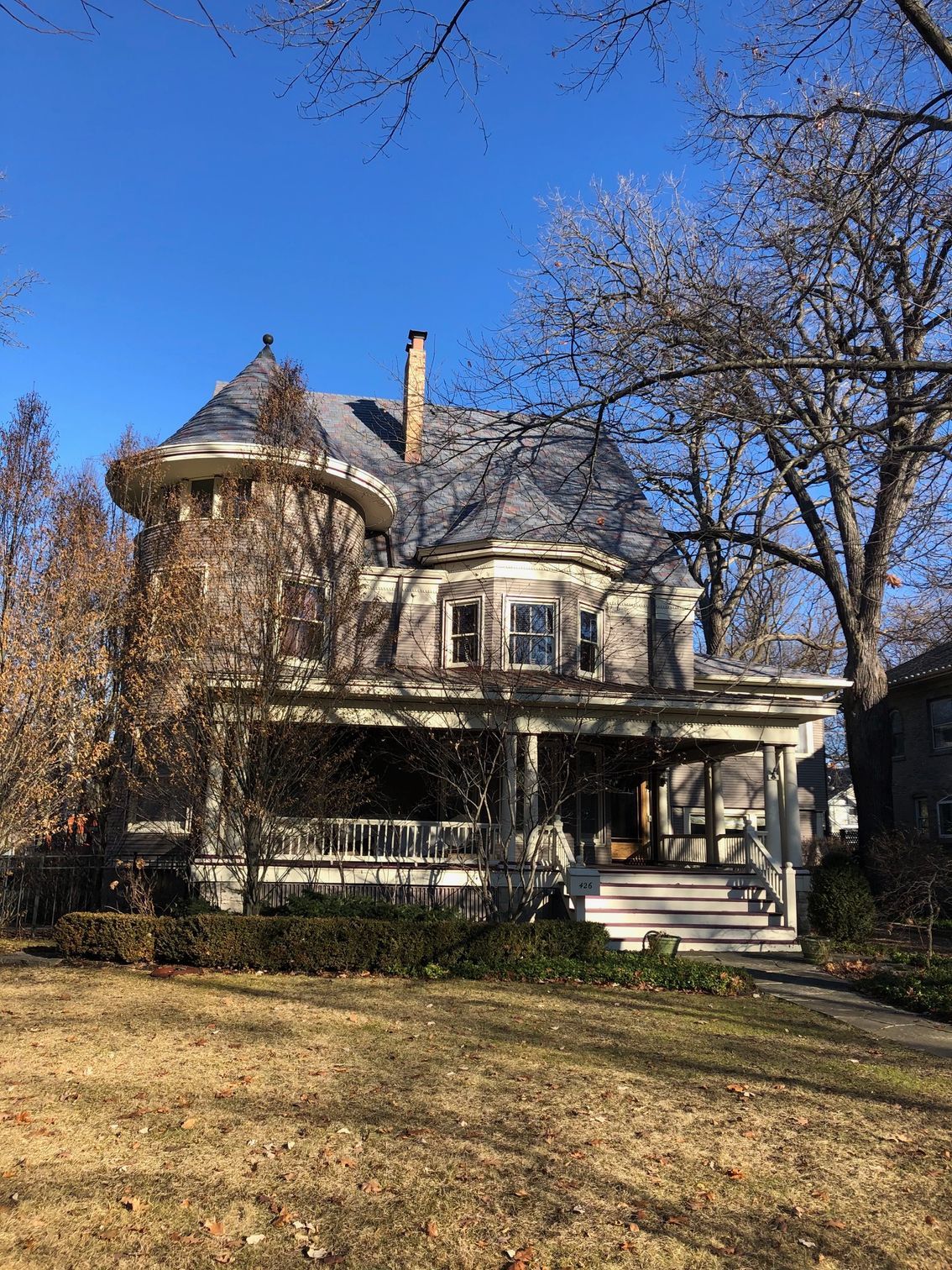 A large house with a tower on top of it is surrounded by trees on a sunny day.
