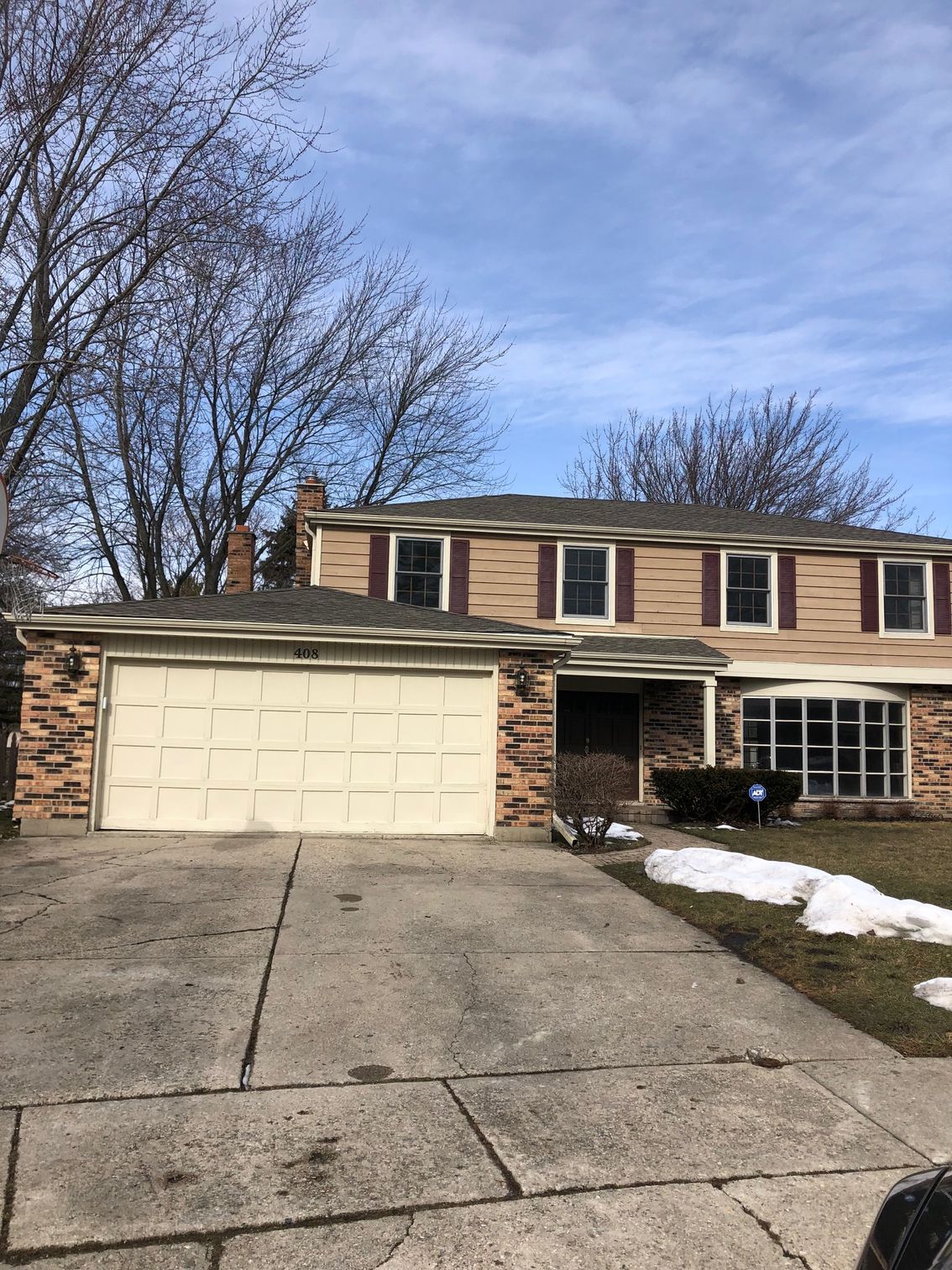 A house with a garage door and a driveway in front of it.
