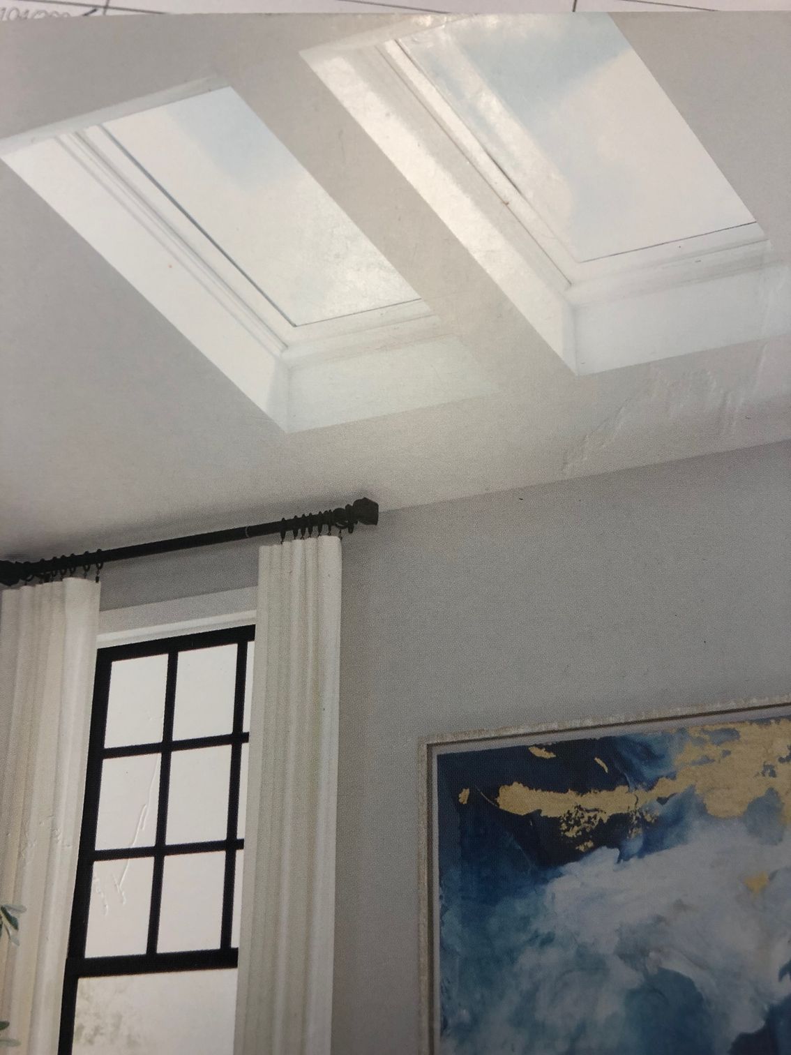 A room with two skylights and a painting on the wall