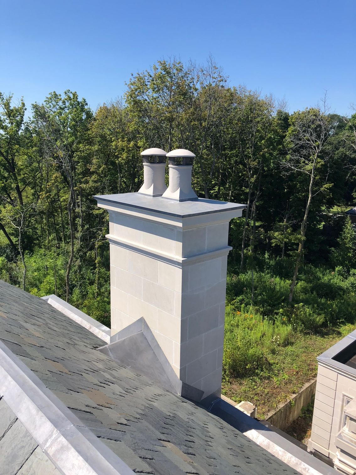 A chimney on top of a roof with trees in the background.