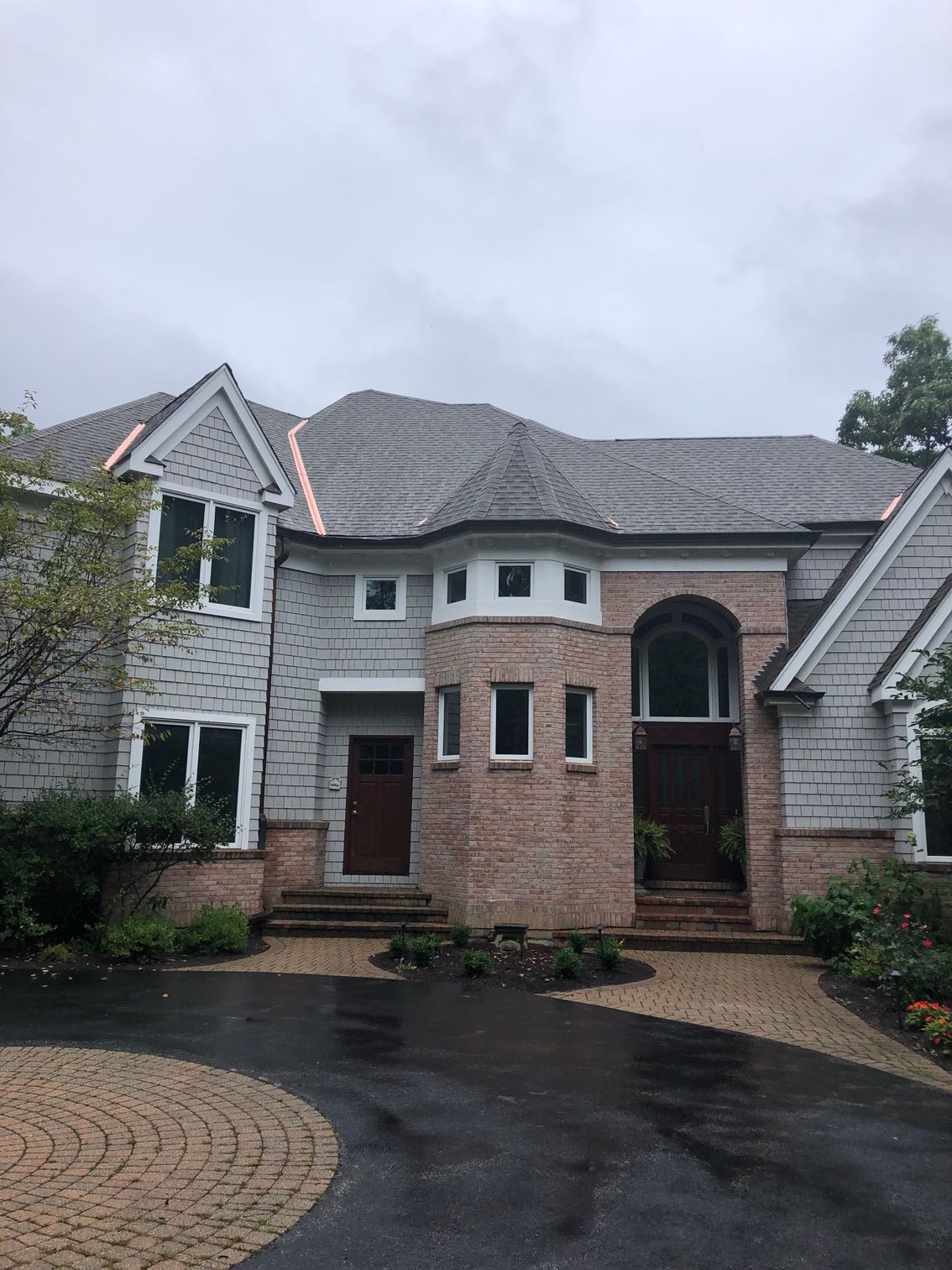 A large brick house with a large driveway in front of it.