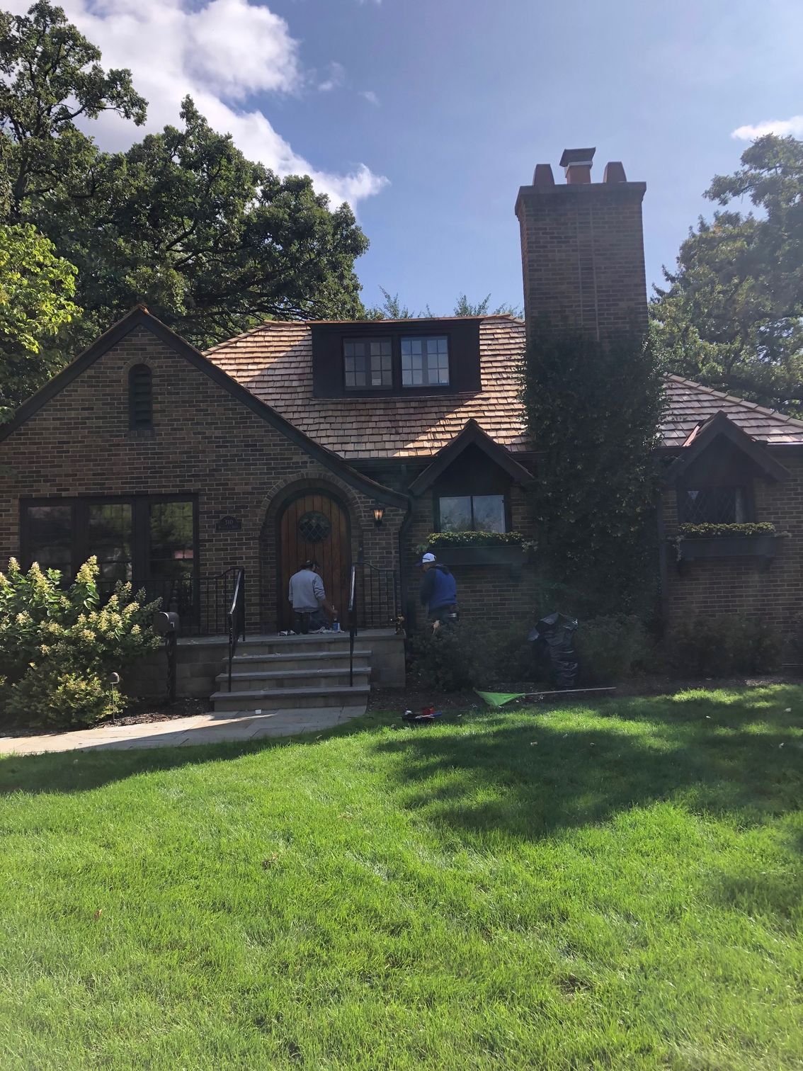 A brick house with a chimney and a large lawn in front of it