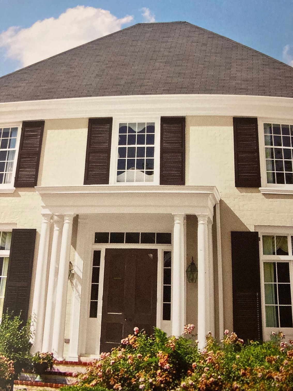A white house with brown shutters on the windows