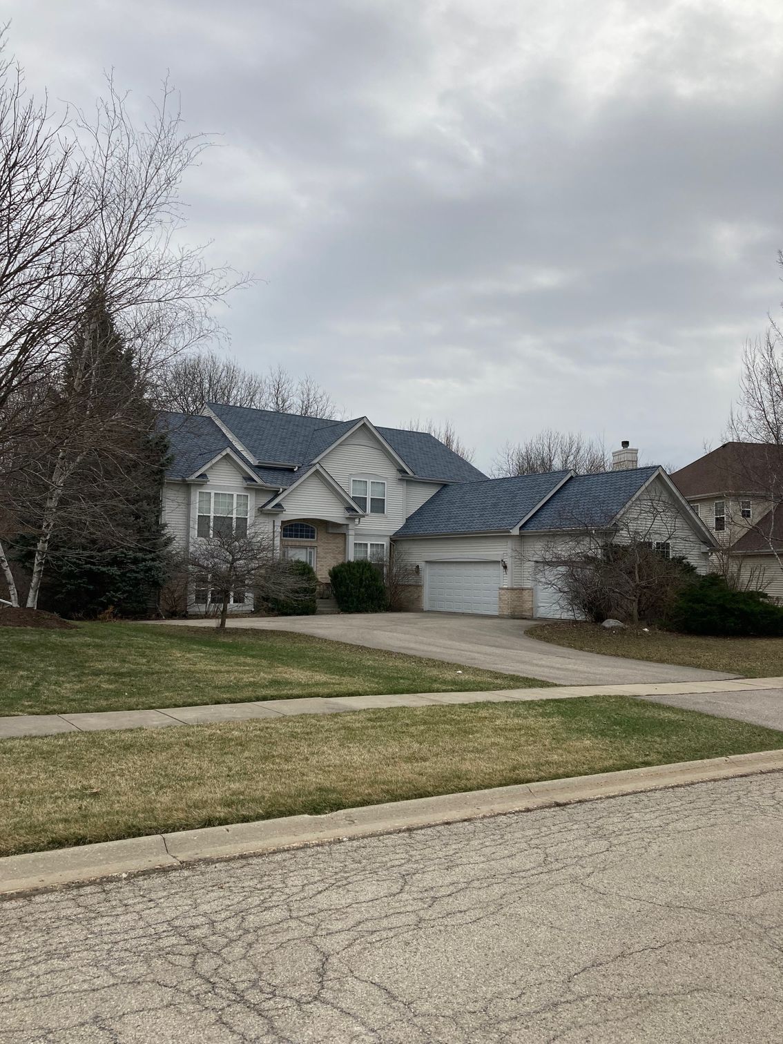 A large white house with a blue roof in a residential neighborhood.