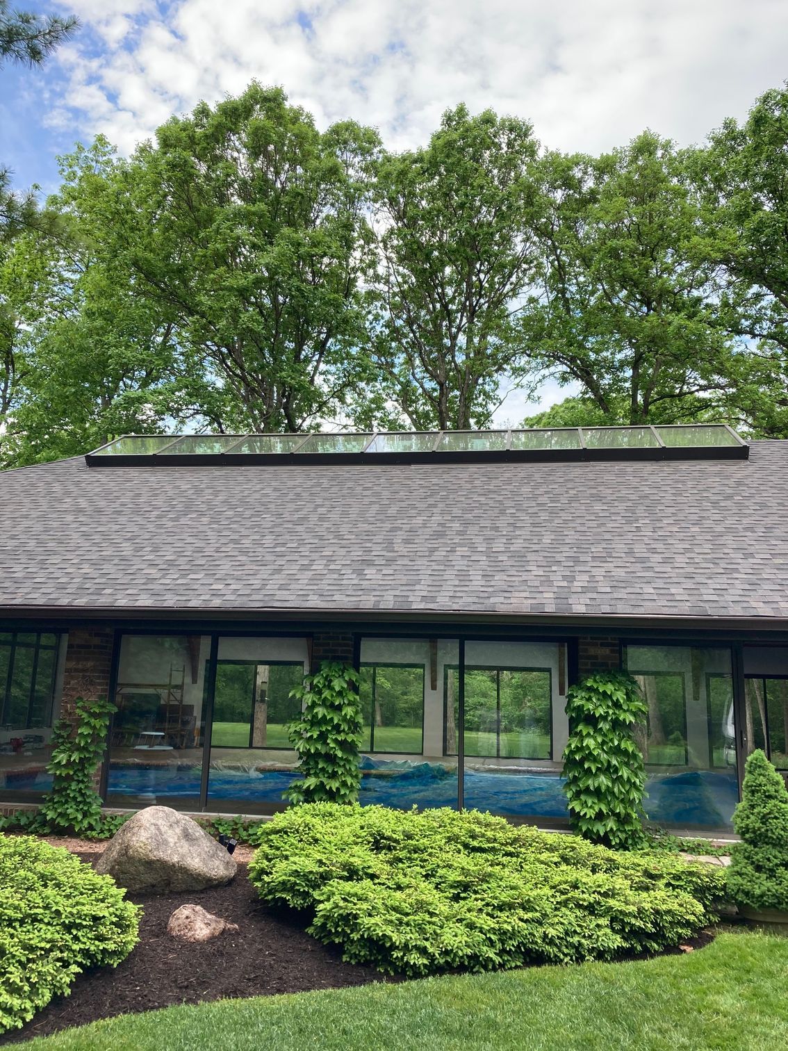 A house with a large swimming pool in the backyard surrounded by trees.