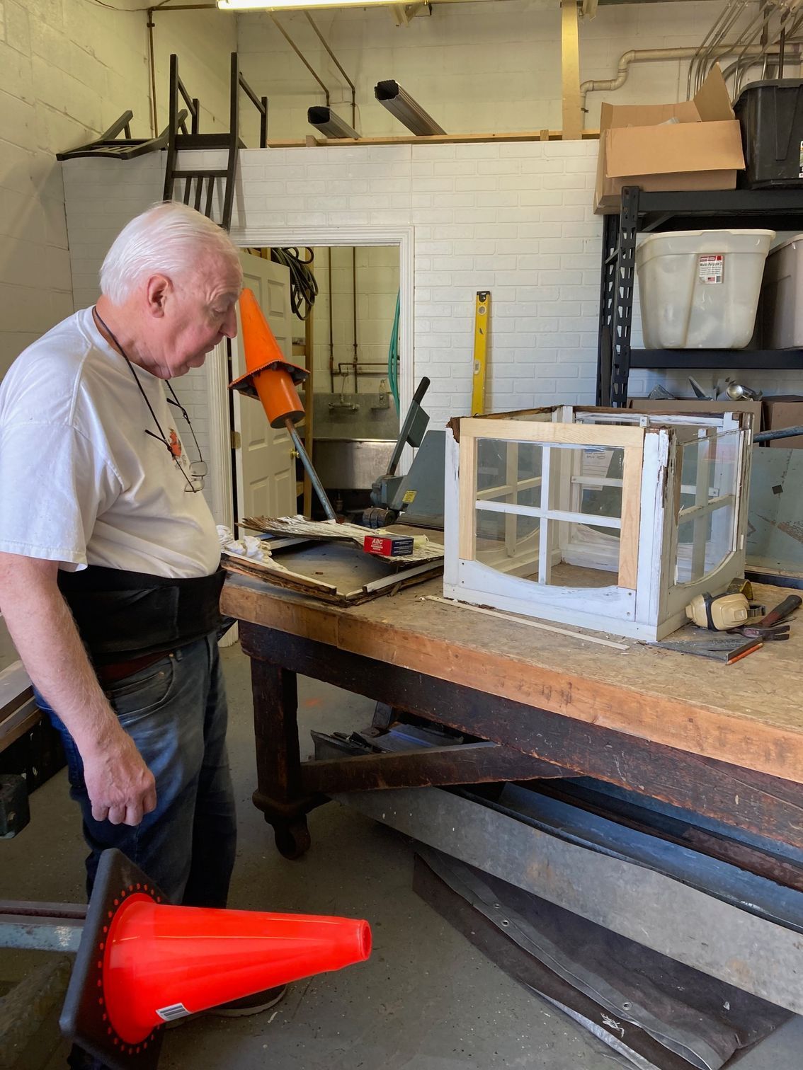 A man is standing next to an orange cone in a workshop.