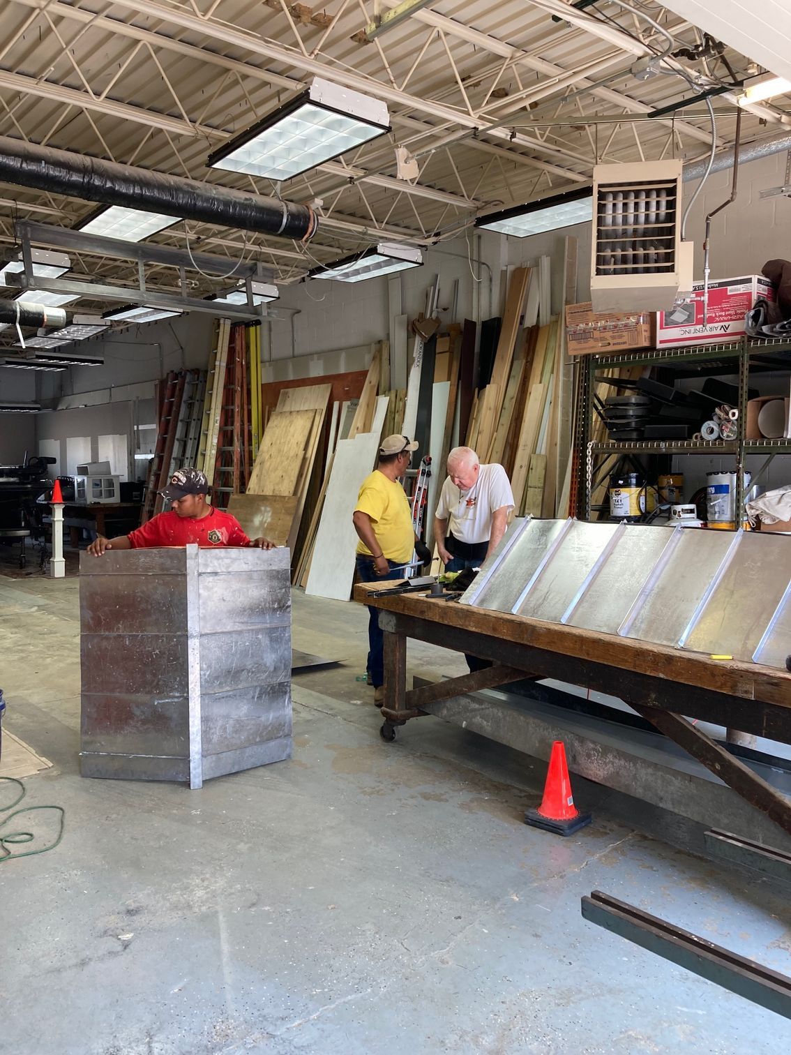 A man is holding a large piece of metal in front of a house.