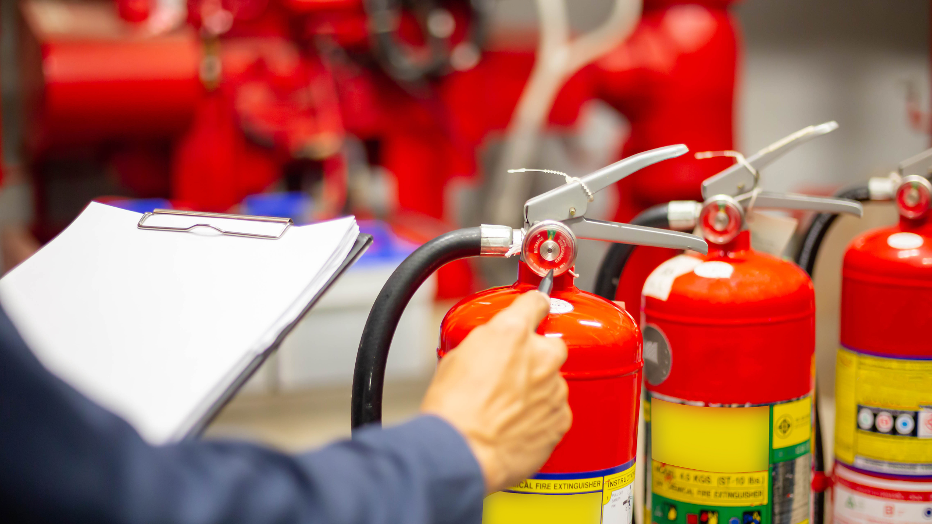 Person inspecting a red fire extinguisher with a clipboard in a mechanical room.
