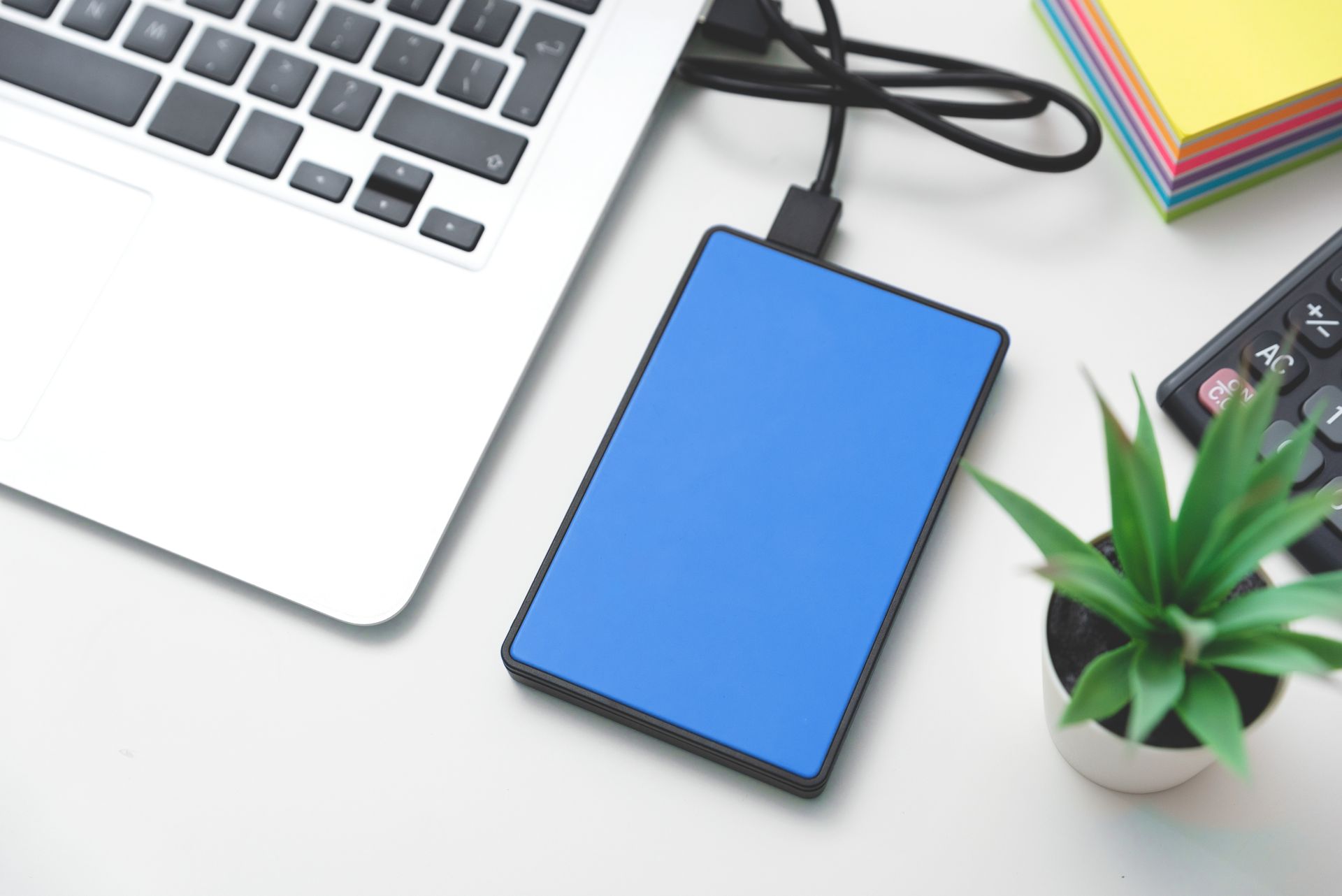A blue external hard drive is plugged into a laptop.