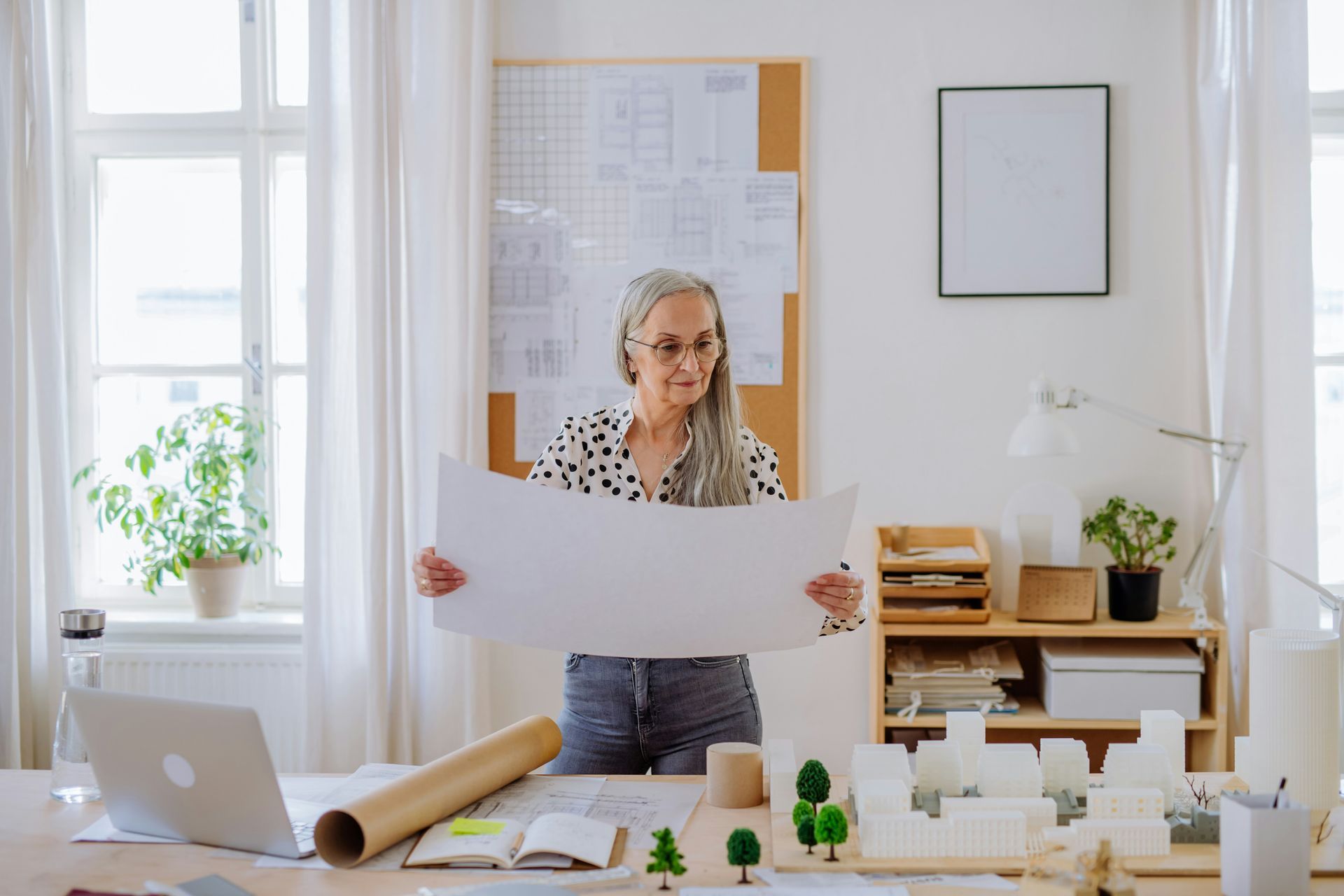 A woman is holding a large piece of paper in an office.