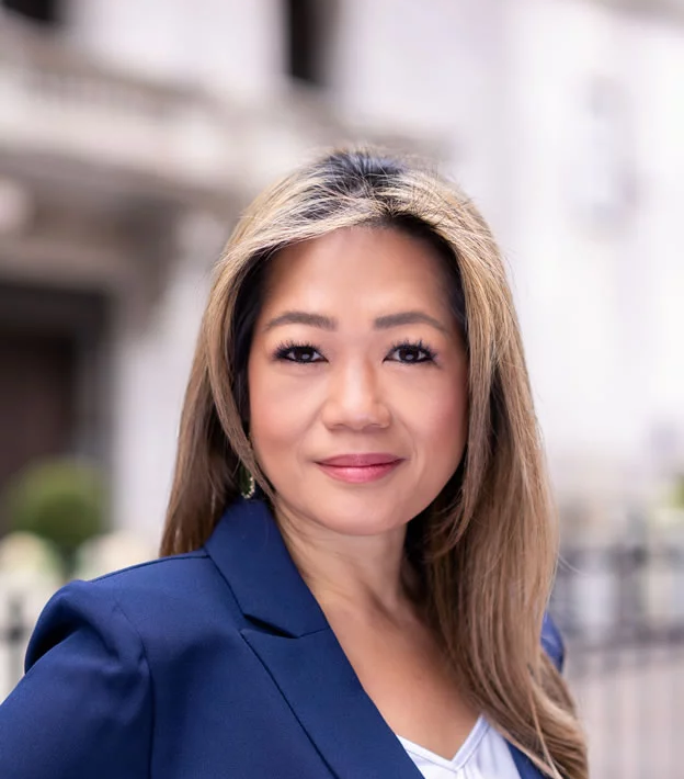 A woman in a blue suit is standing in front of a building.