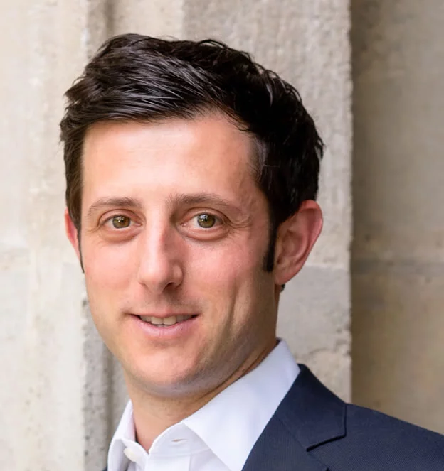 A man in a suit and white shirt is smiling for the camera.