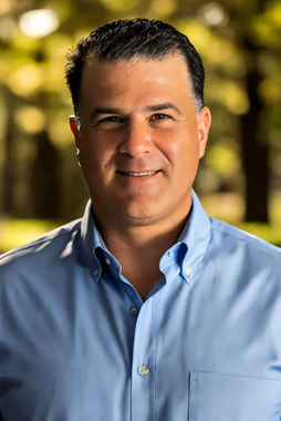 A man in a blue shirt is smiling for the camera.