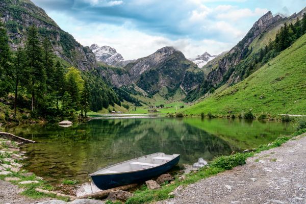 A boat is sitting on the shore of a lake in the mountains.