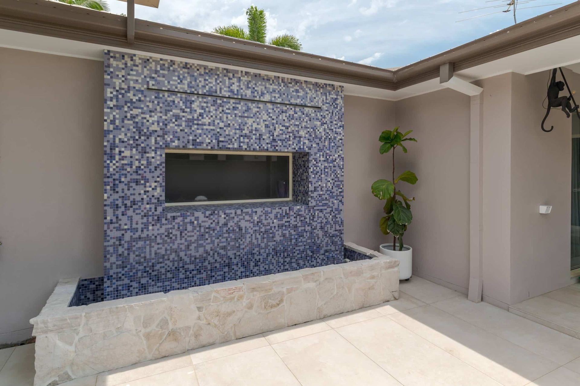 Outdoor mosaic feature wall with blue tiles and stone base – Samford project
