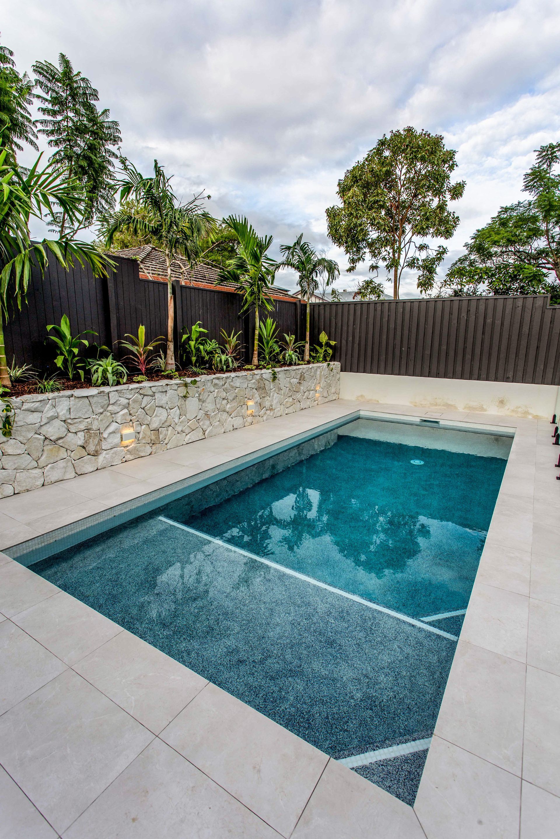 Pool area with stone retaining wall and tiled surround – Camp Hill project