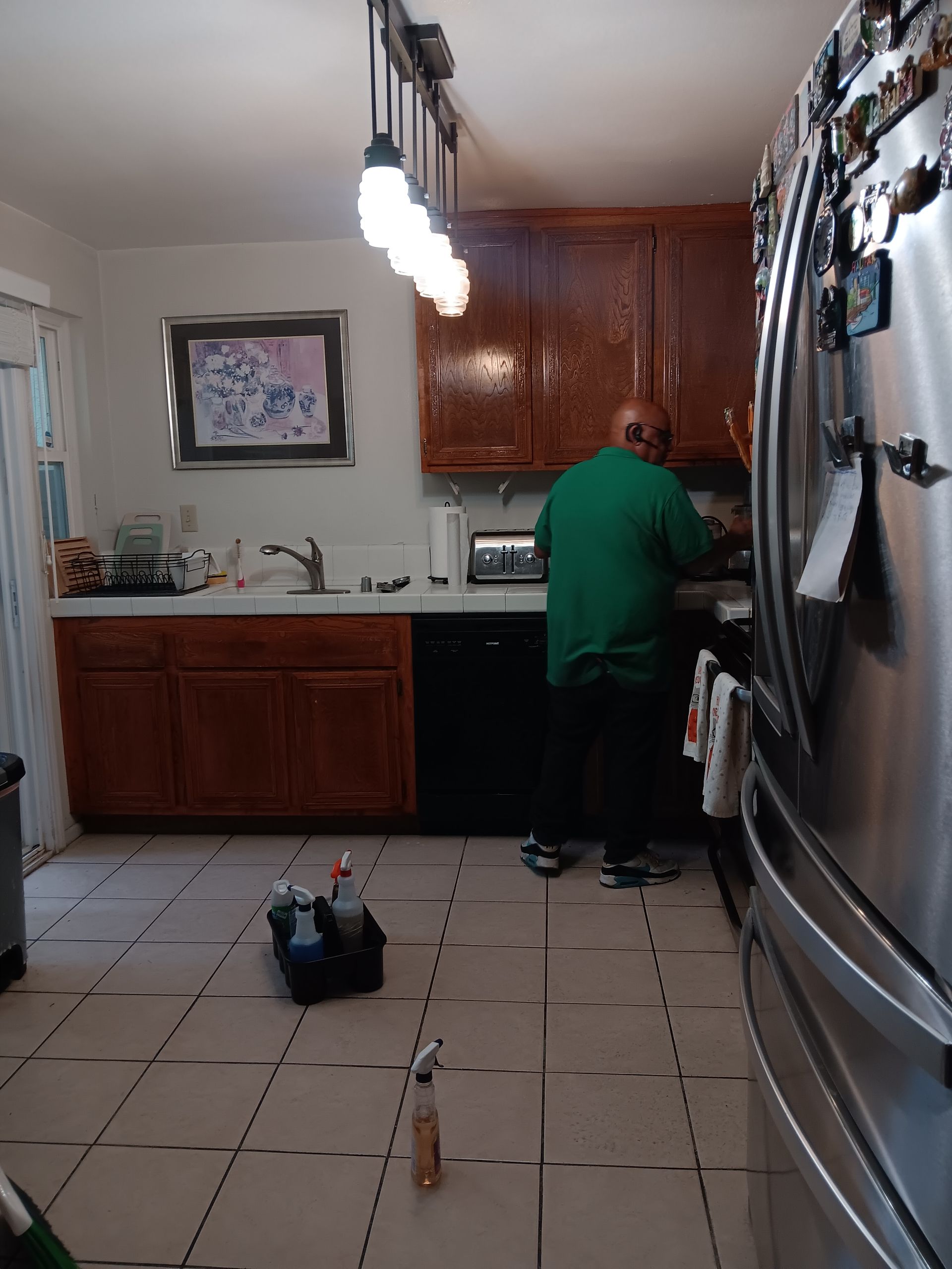 A man in a green shirt is working in a kitchen.