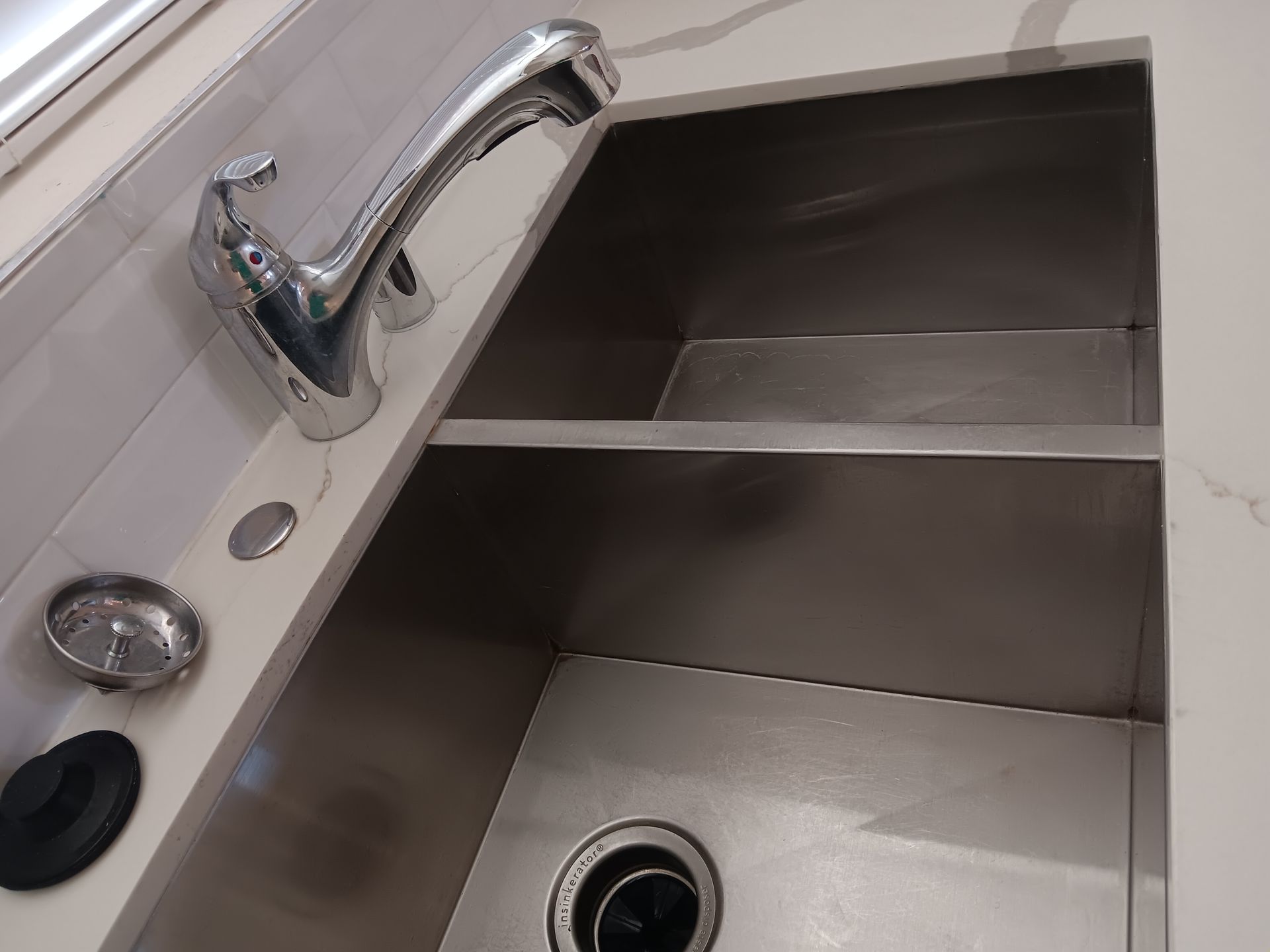 A stainless steel kitchen sink with a faucet and garbage disposal