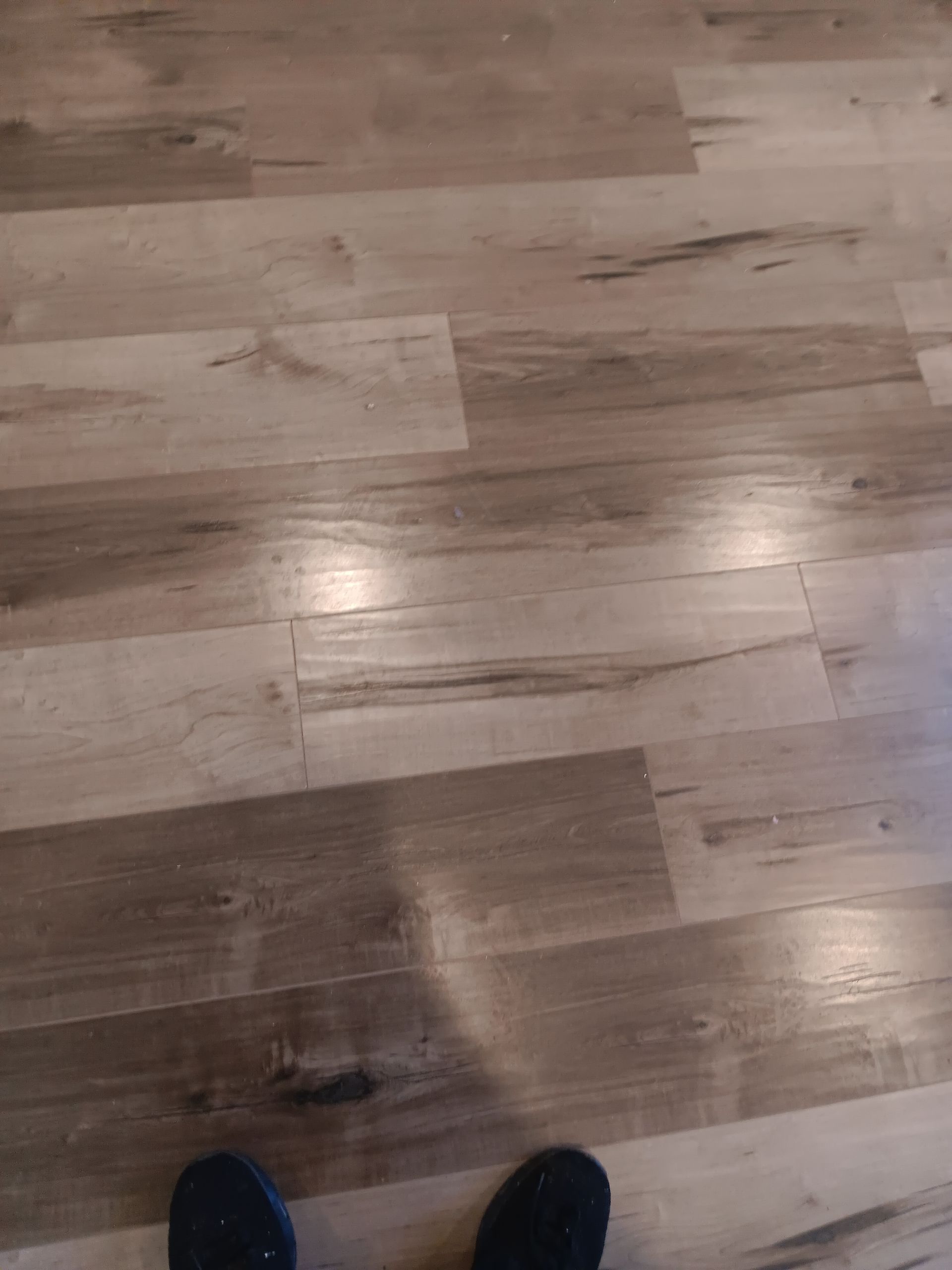 A person is standing on a wooden floor in a room.