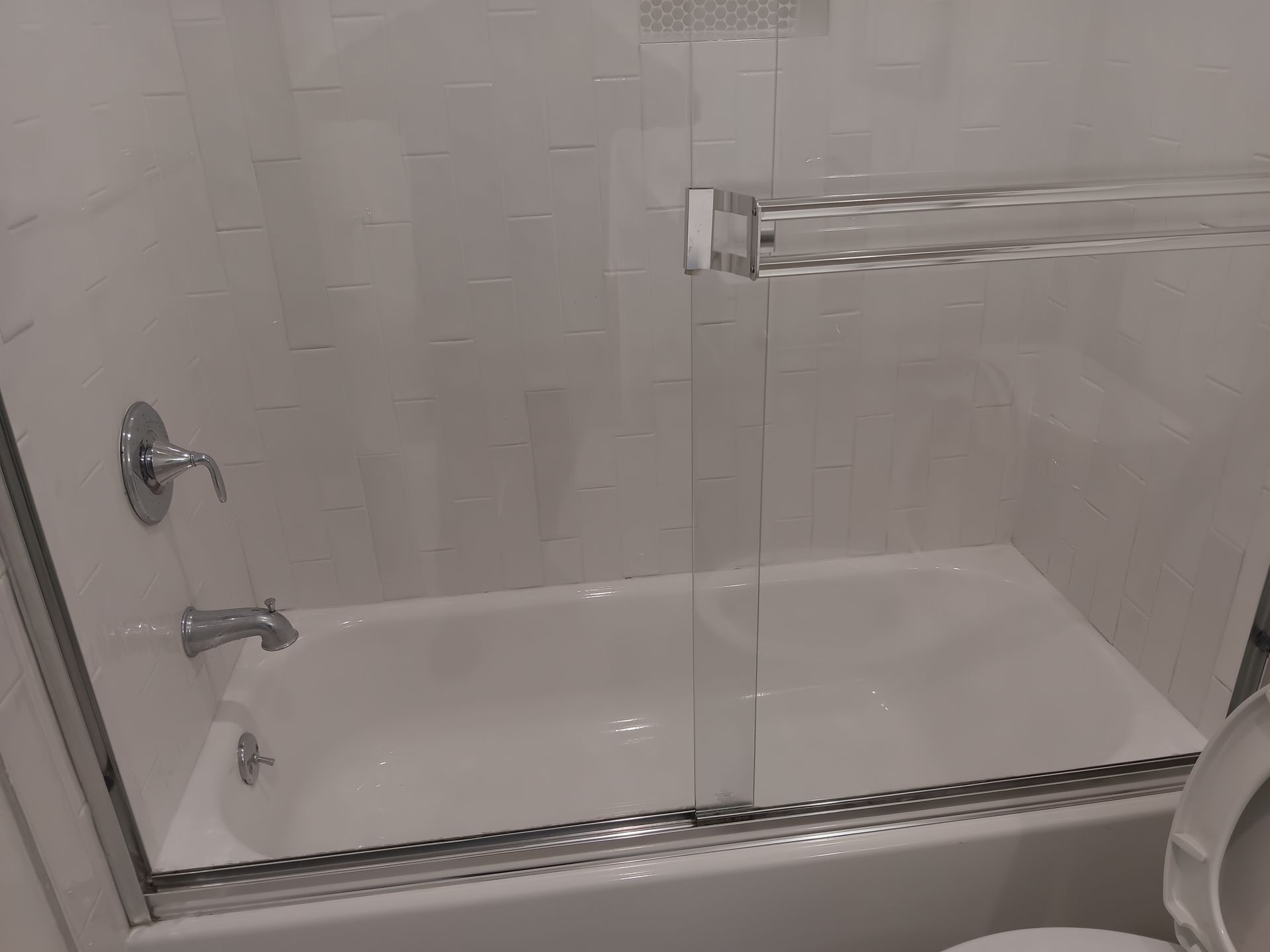 A bathroom with a bathtub , toilet , shower and glass door.