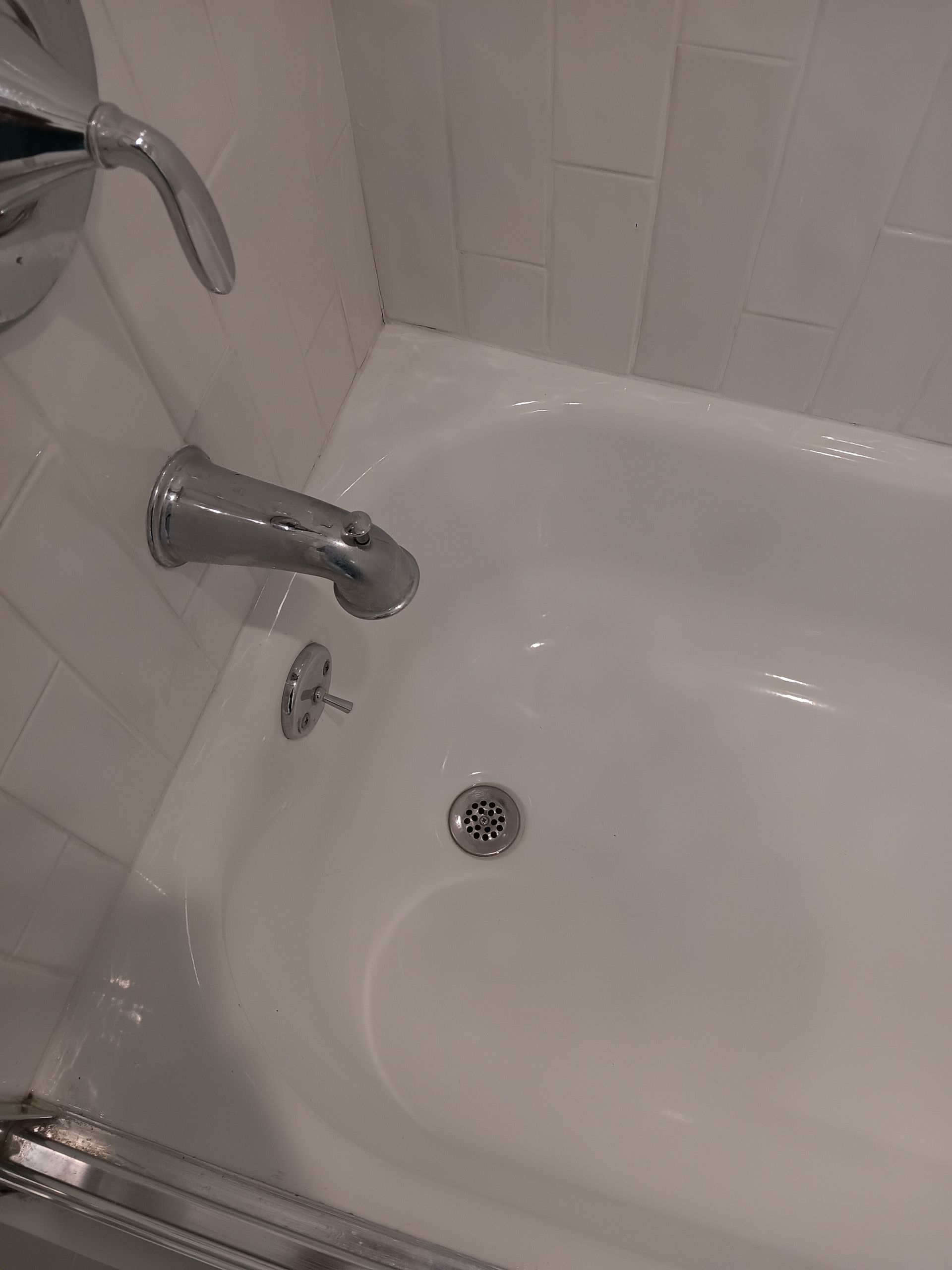 A white bathtub with a chrome faucet and drain in a bathroom.