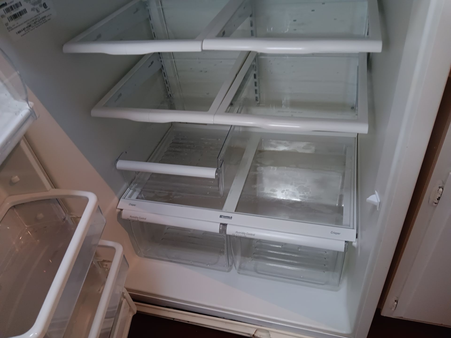The inside of a refrigerator with empty shelves and drawers.