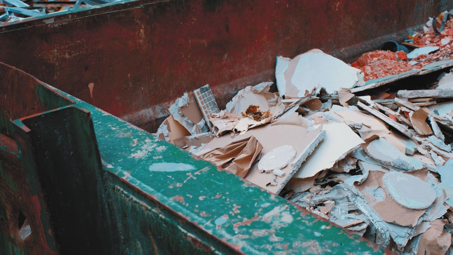 A green dumpster filled with a pile of cardboard.