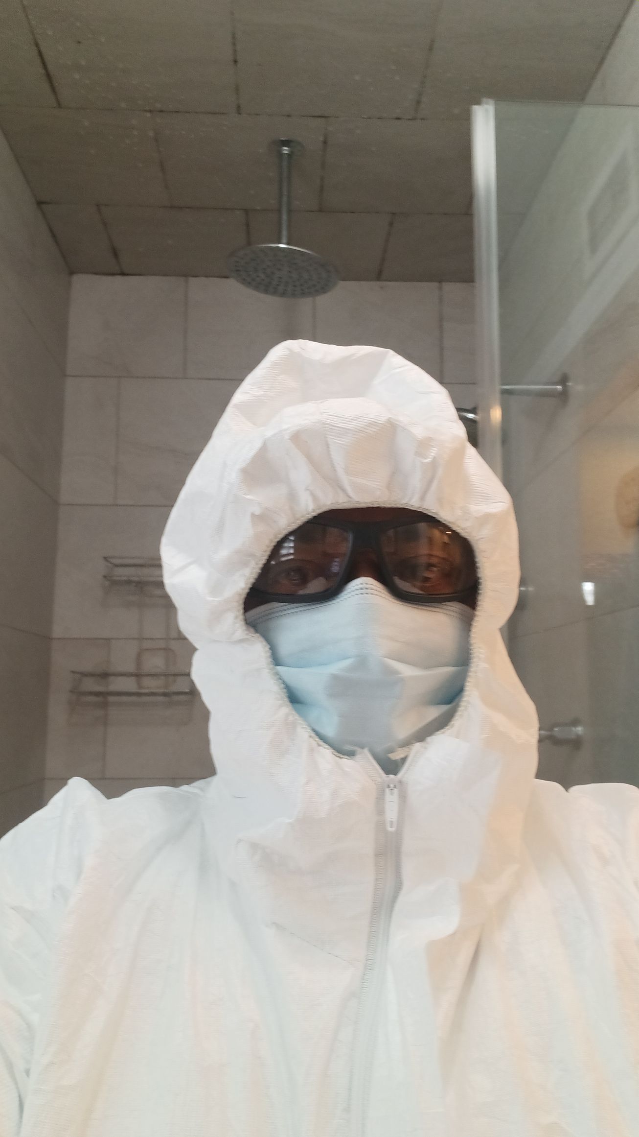 A person wearing a protective suit , mask and goggles.