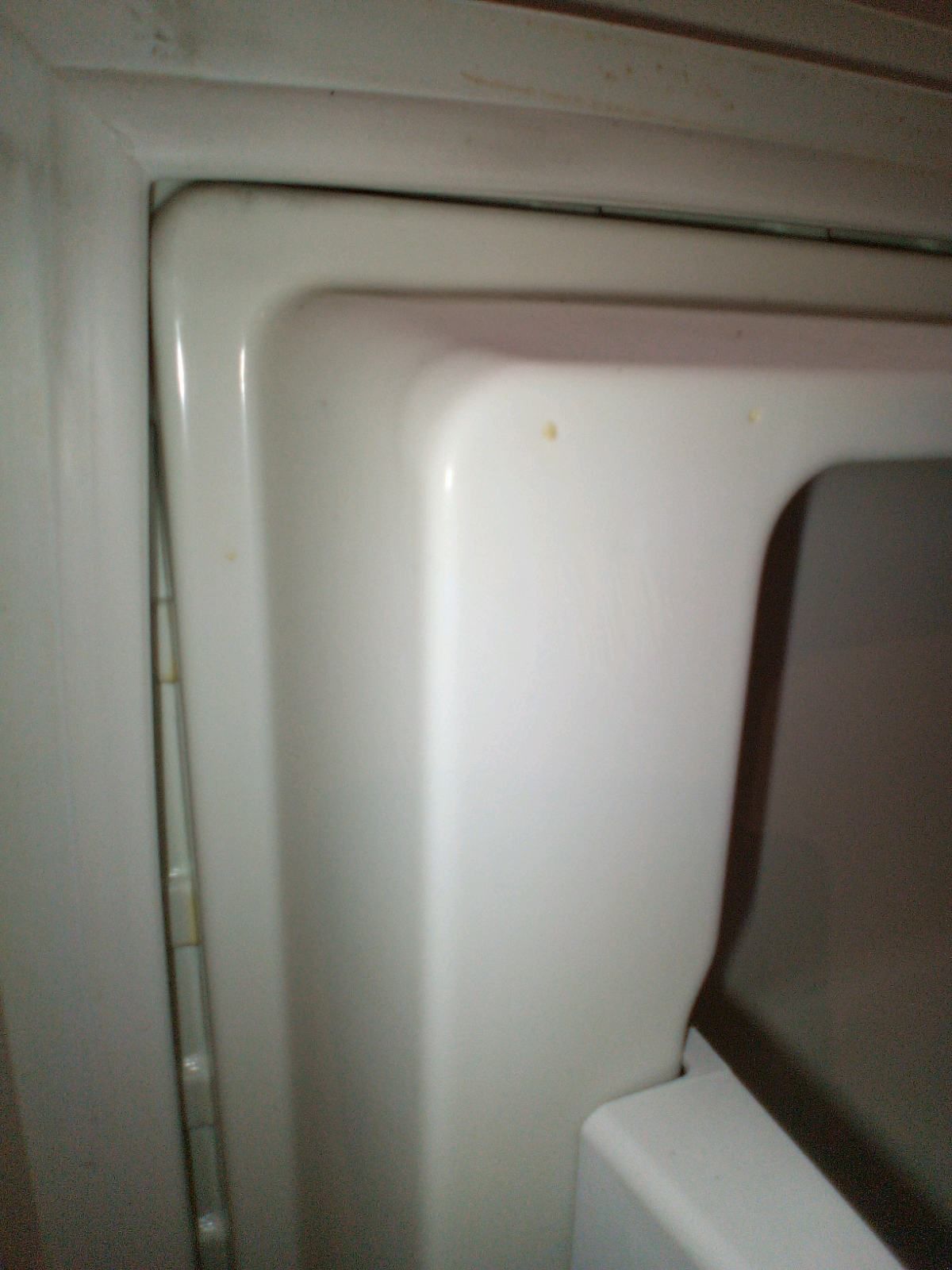 A close up of the corner of a white refrigerator.