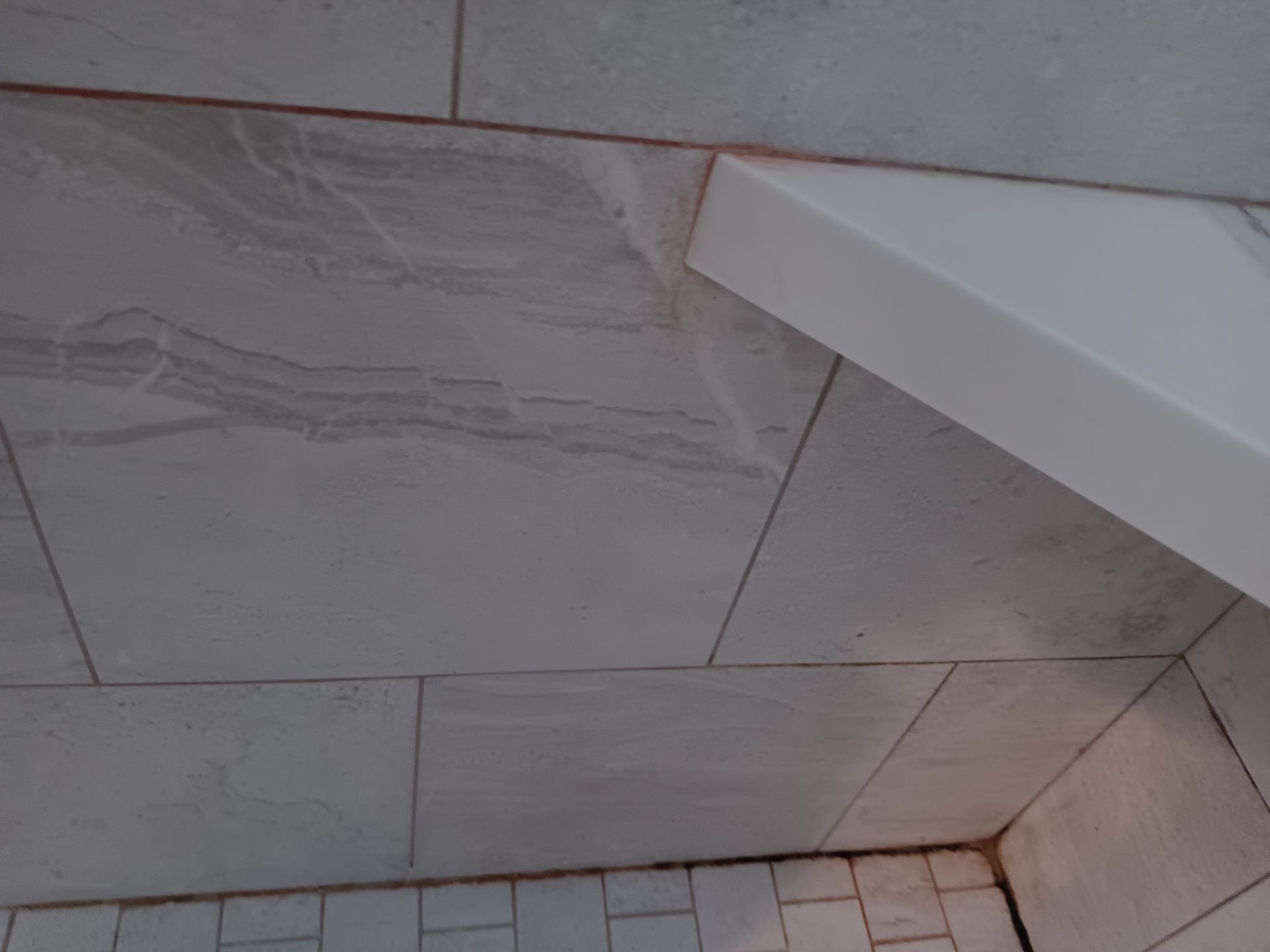 A white tile ceiling with a white shelf in the corner