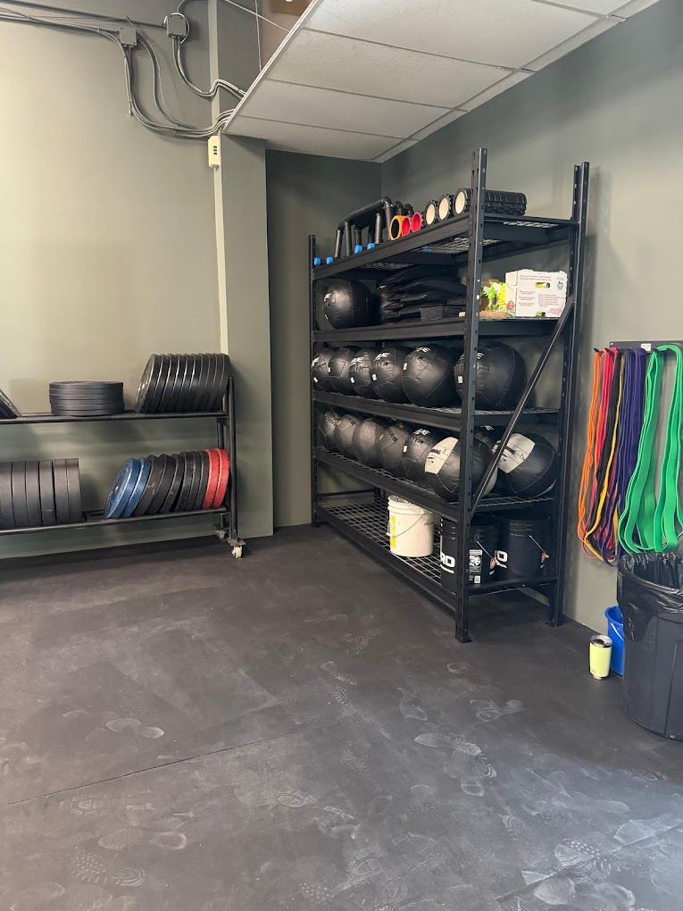 A room with a lot of shelves filled with dumbbells and resistance bands.