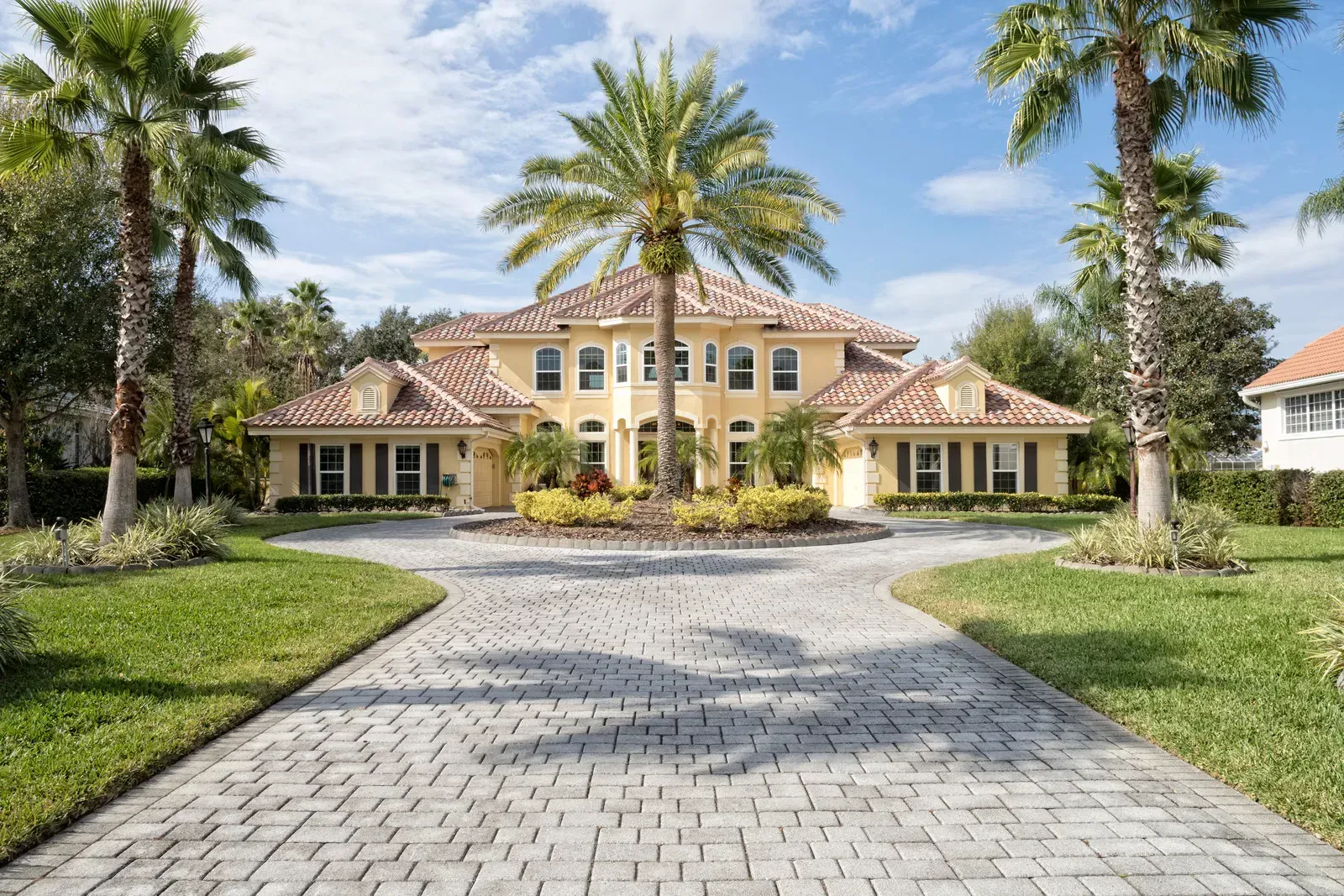A large yellow house with palm trees in front of it
