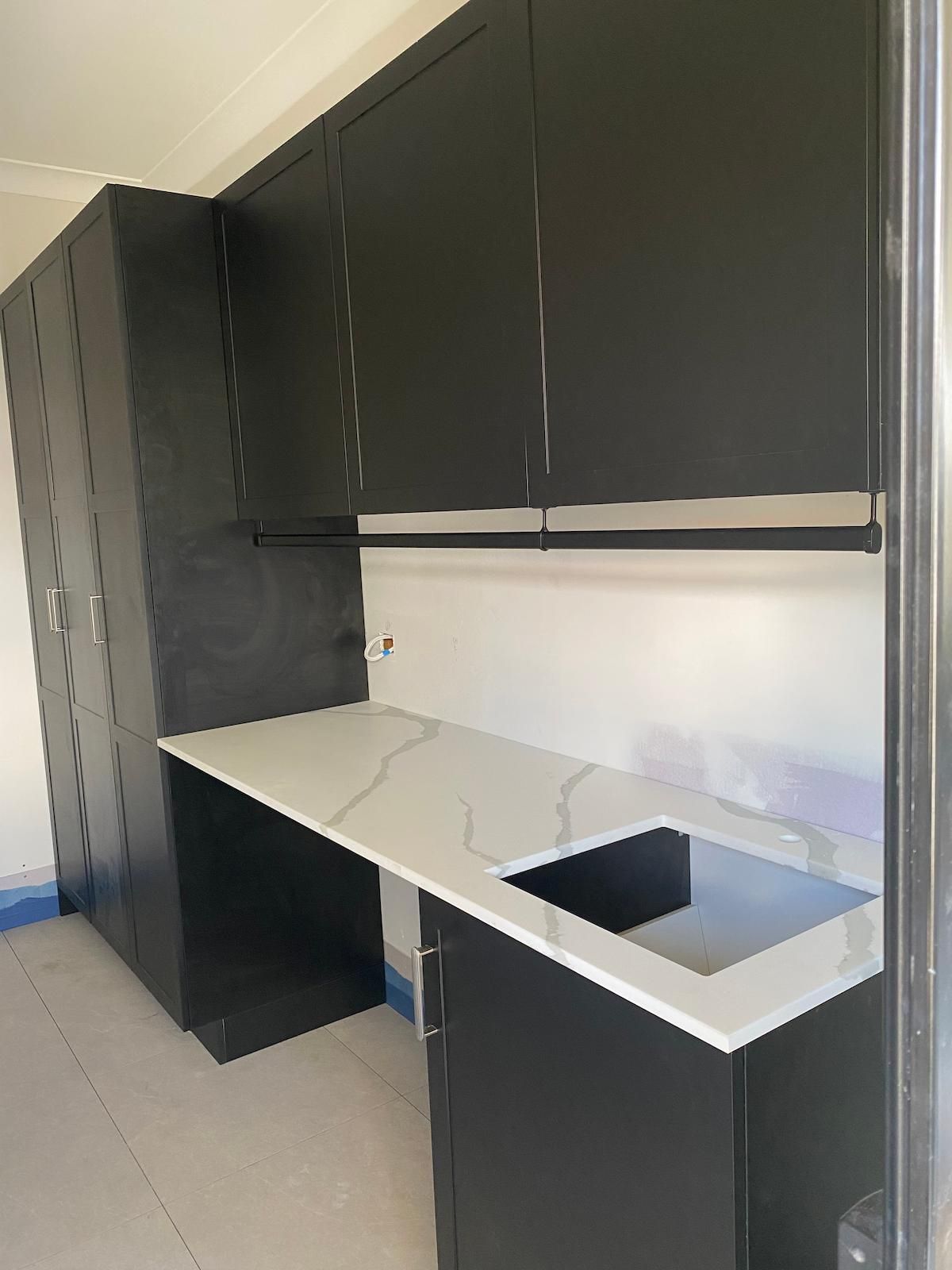 A Kitchen With Black Cabinets and a White Counter Top — Nick Hall Builder in Noosa, QLD