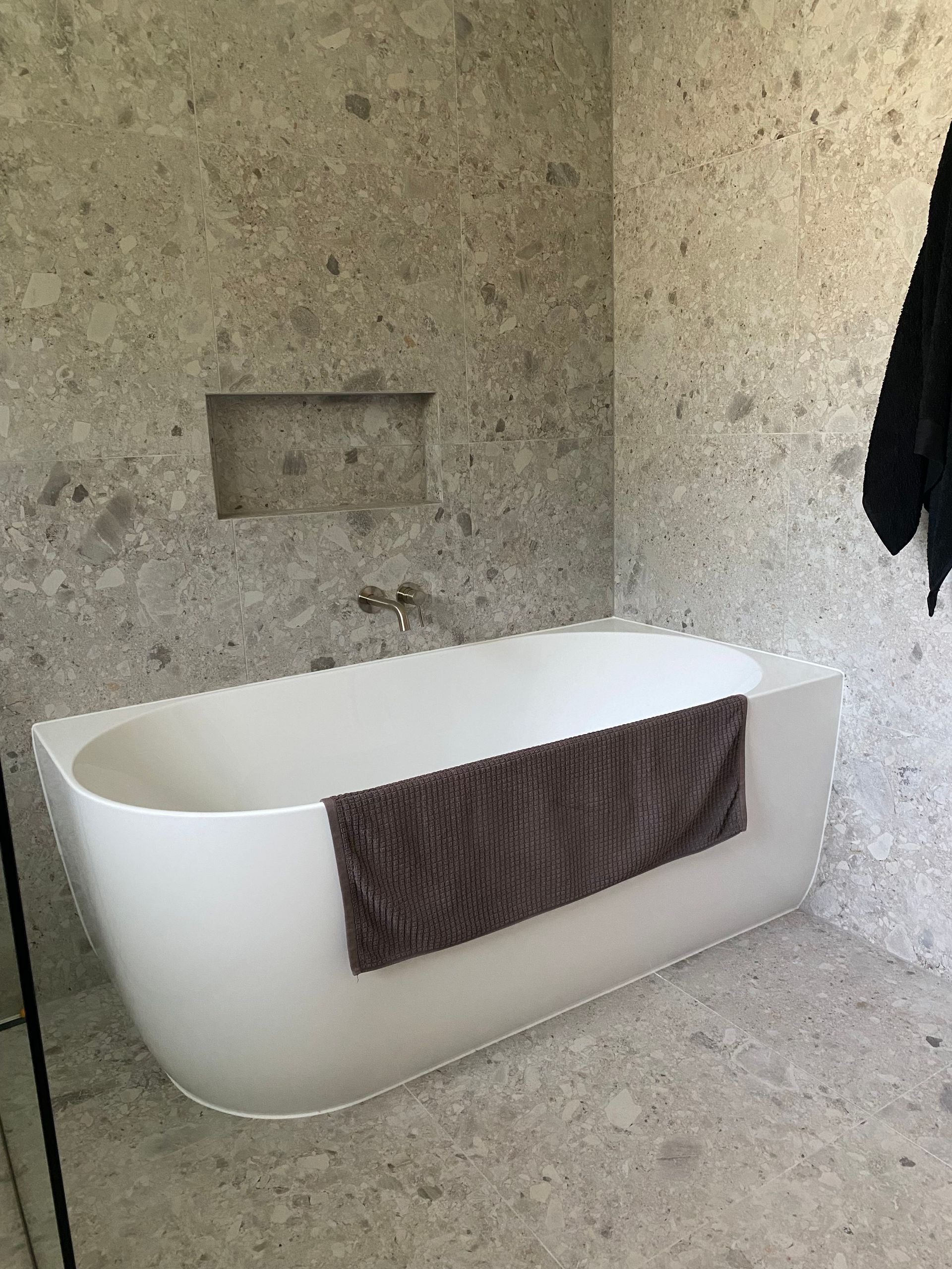 A White Freestanding Bathtub With a Dark Towel Draped Over the Side — Nick Hall Builder in Cooroy, QLD