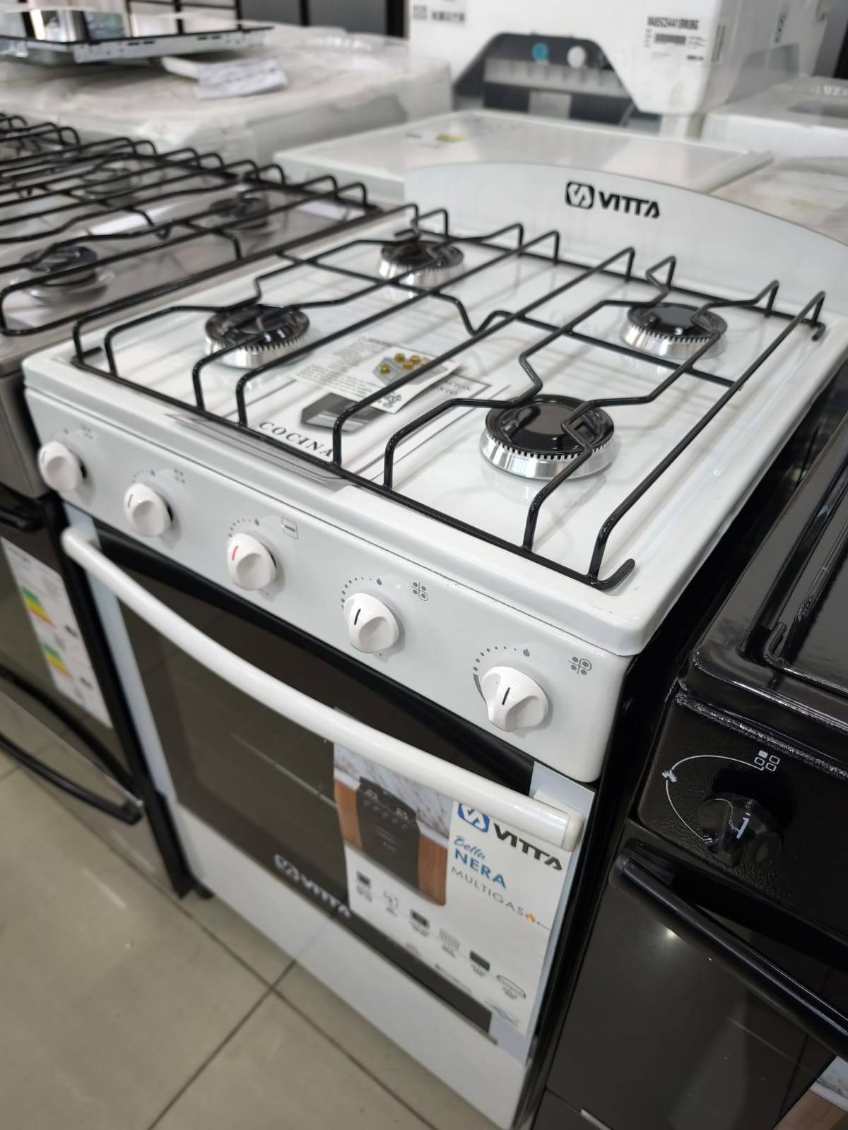 Estufa a gas Vitta blanca con cuatro quemadores, horno y perillas de control.