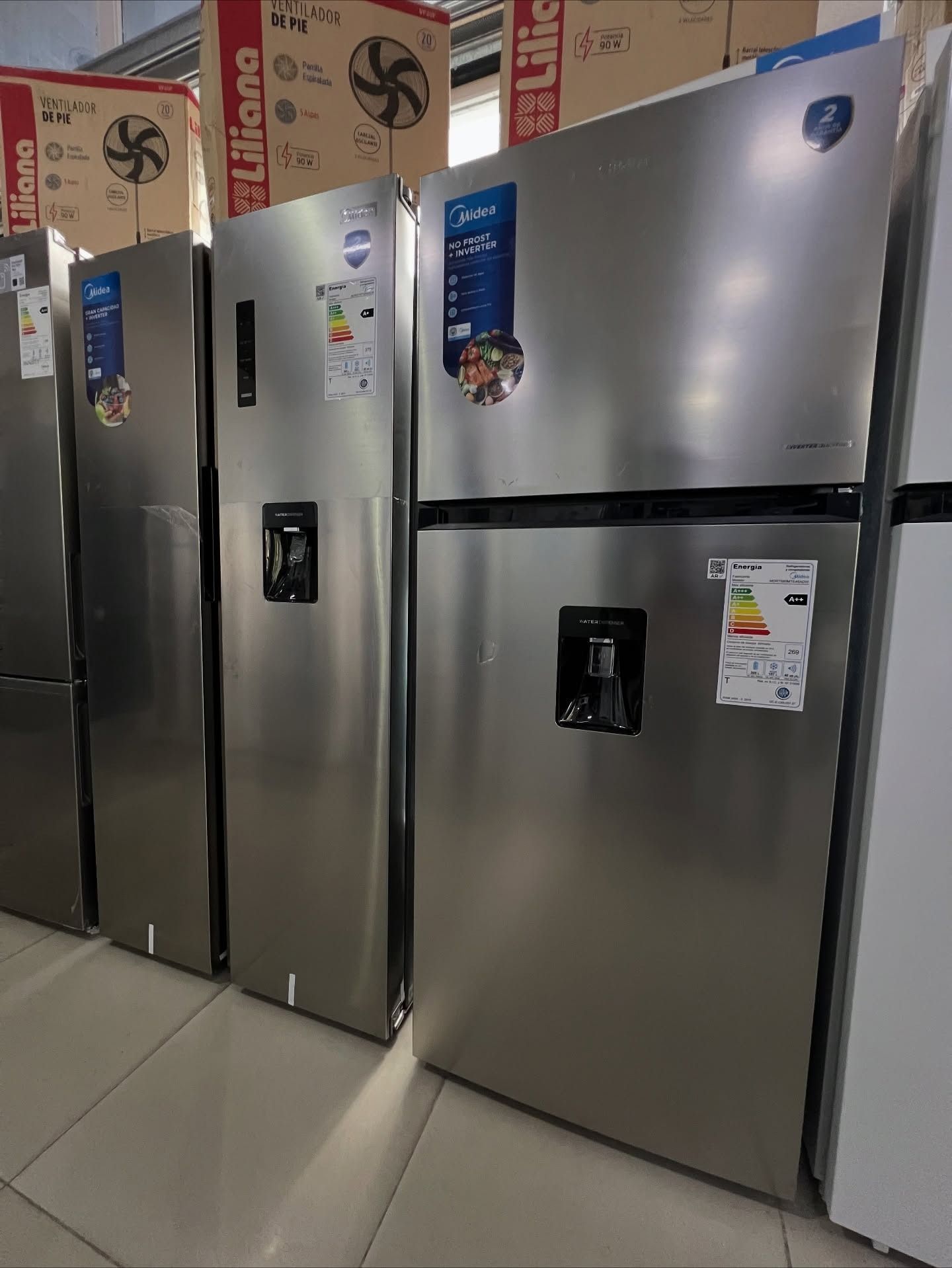 Refrigeradores en exhibición en una tienda; acabado en acero inoxidable, dispensadores de agua, etiquetas energéticas.