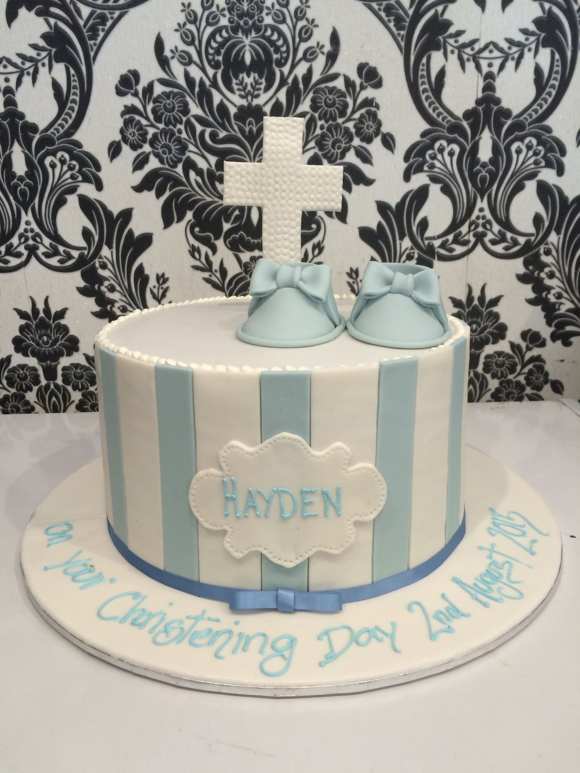 white christening cake with white cross on top and blue panels