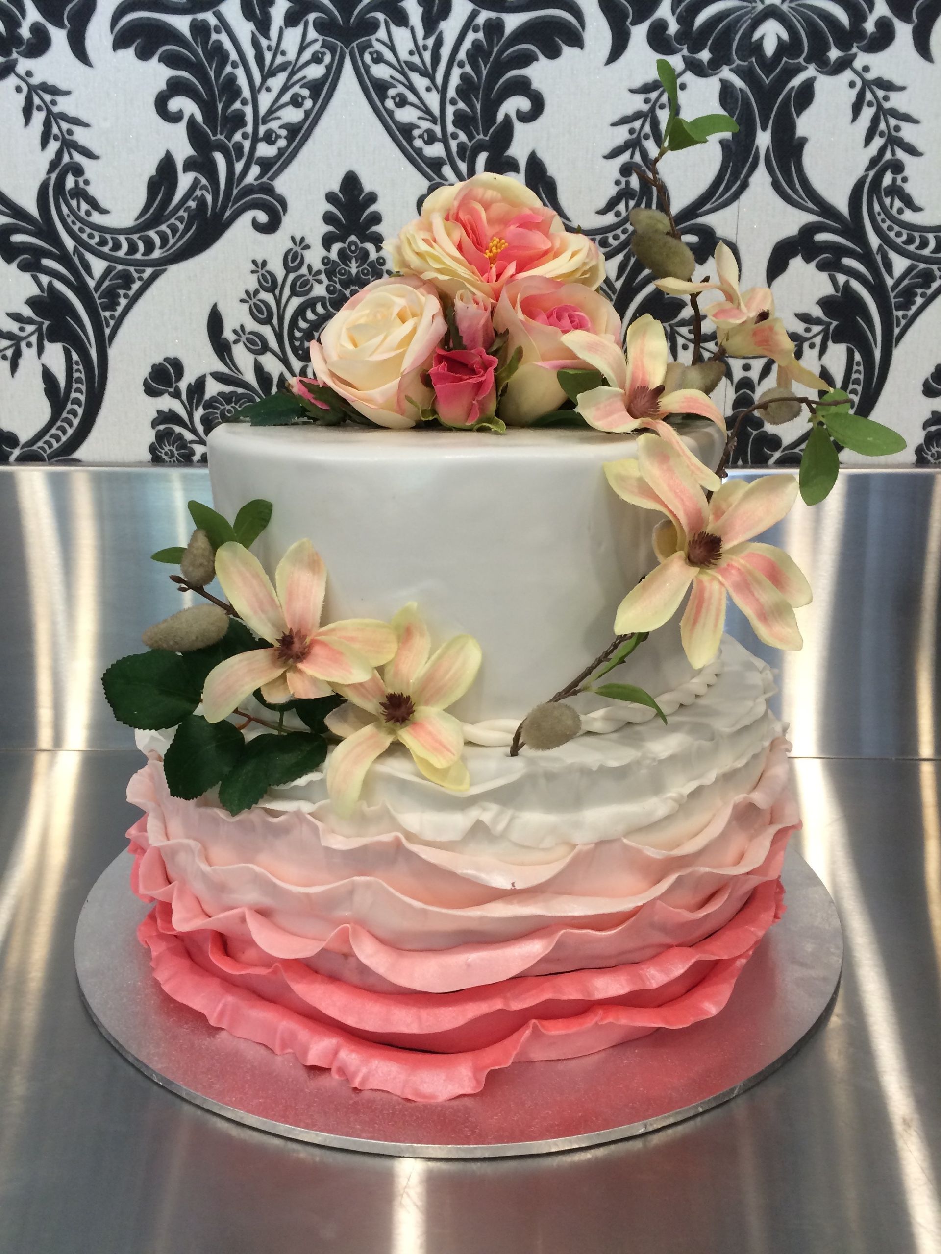 white double tier cake with pink waves and white flowers